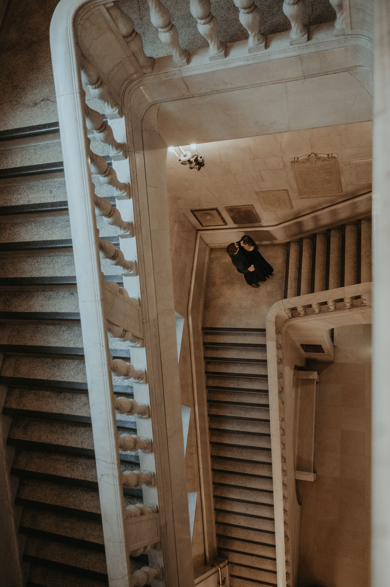 Looking up a spiral staircase with white columns and dark steps creates a mesmerizing architectural pattern.