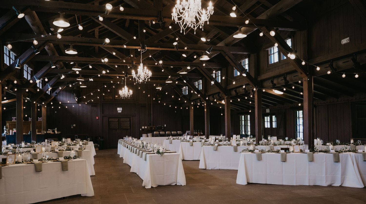 Elegant wedding reception hall with chandeliers and white table settings in panoramic view.