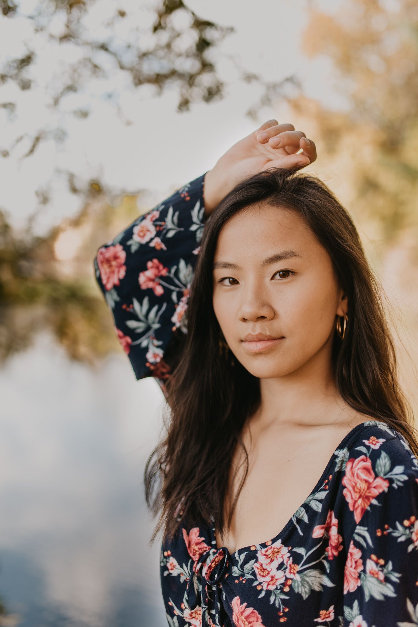 Person in navy floral dress poses gracefully in natural lighting.