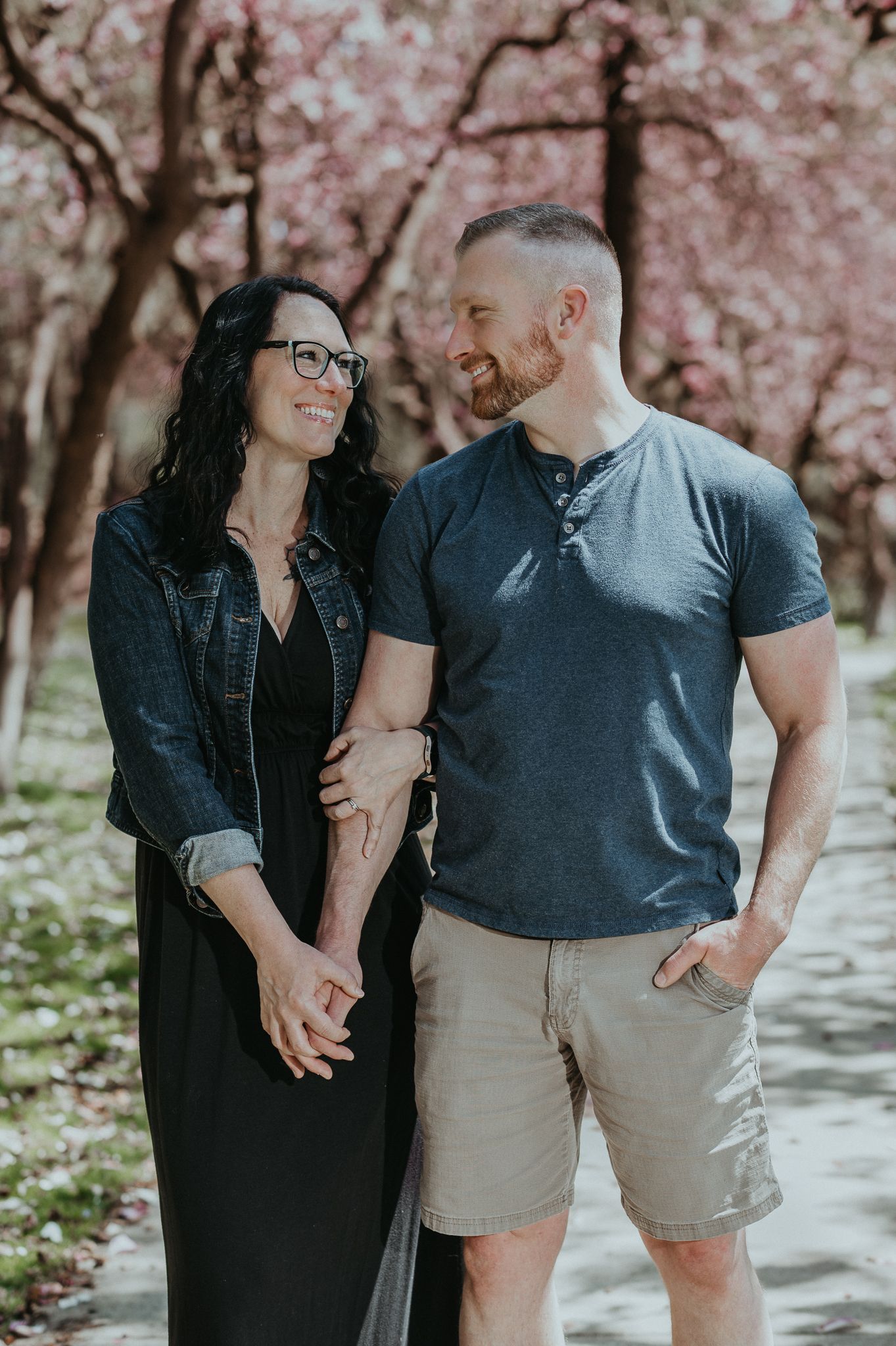 Couple sharing loving glance under blooming cherry blossoms.