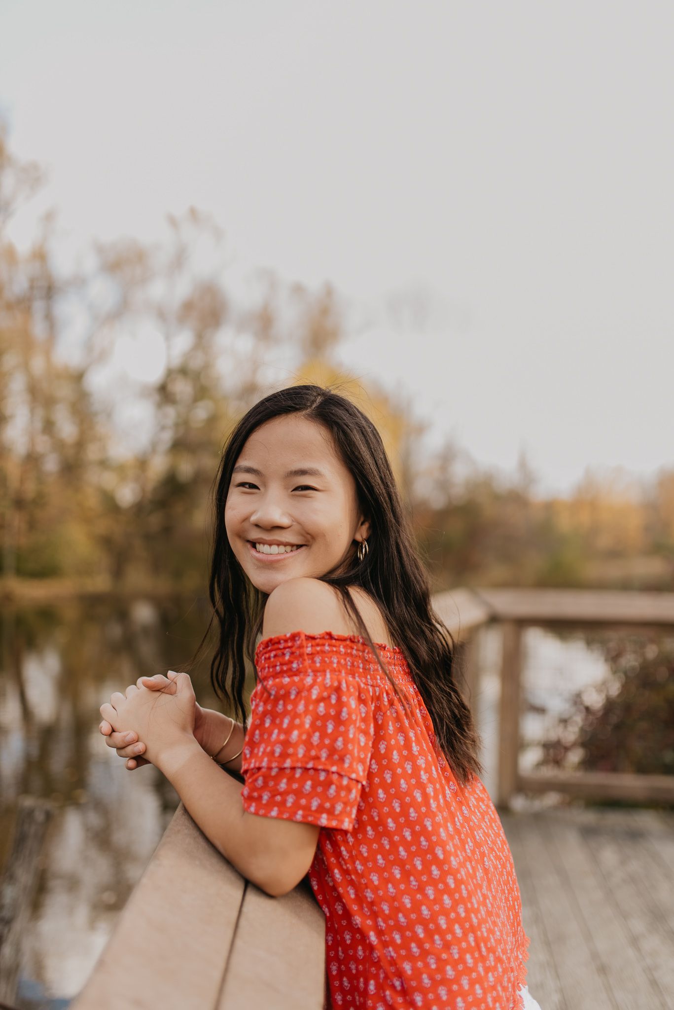 Person in a red polka dot top laughing joyfully in a series of candid outdoor portraits.