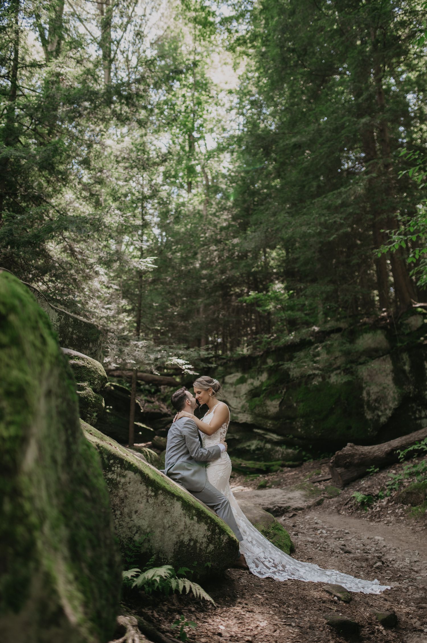 Romantic forest wedding photo session among tall trees and natural scenery.