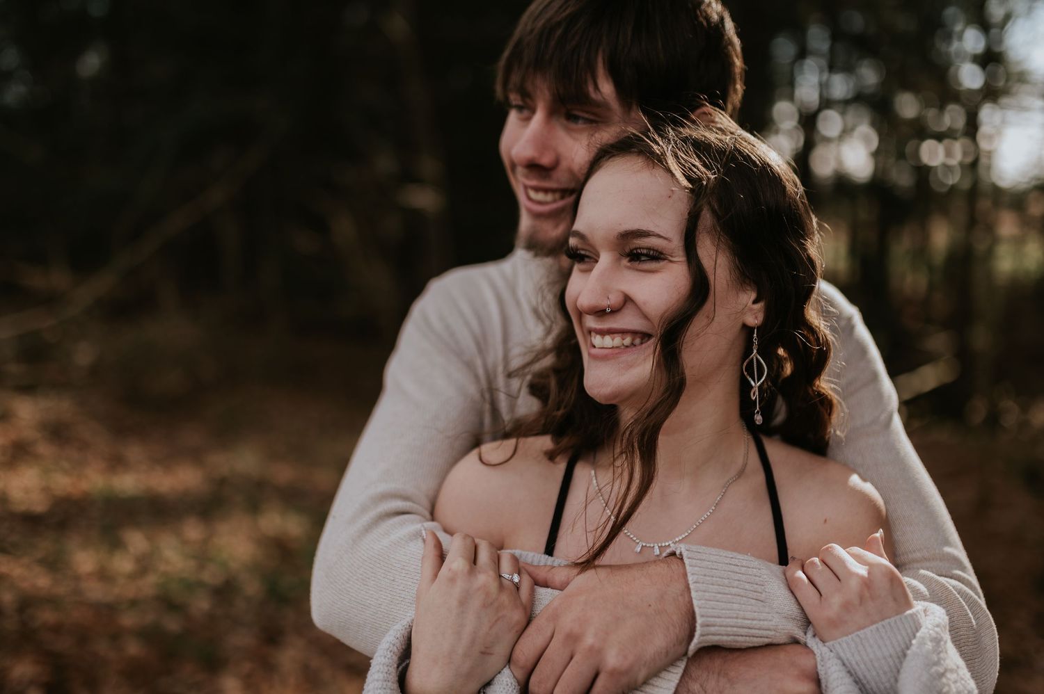 A couple shares romantic moments during their woodland engagement photoshoot at golden hour.