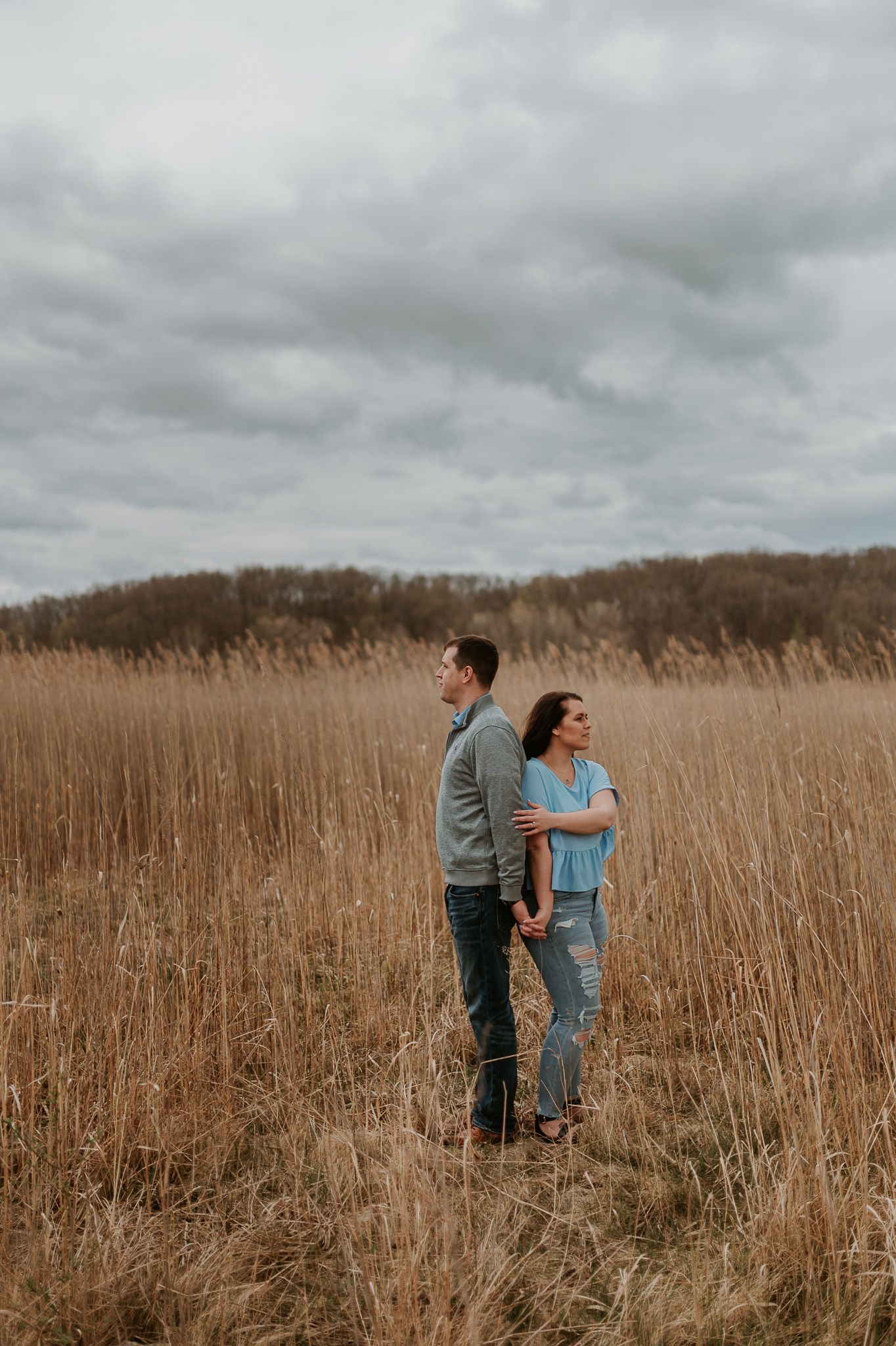 Walking together through tall dried grass during a moody fall photoshoot.