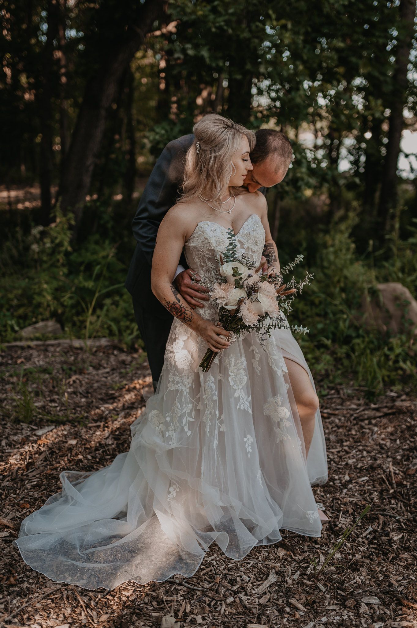 Romantic woodland portrait of couple with bride holding delicate floral bouquet.