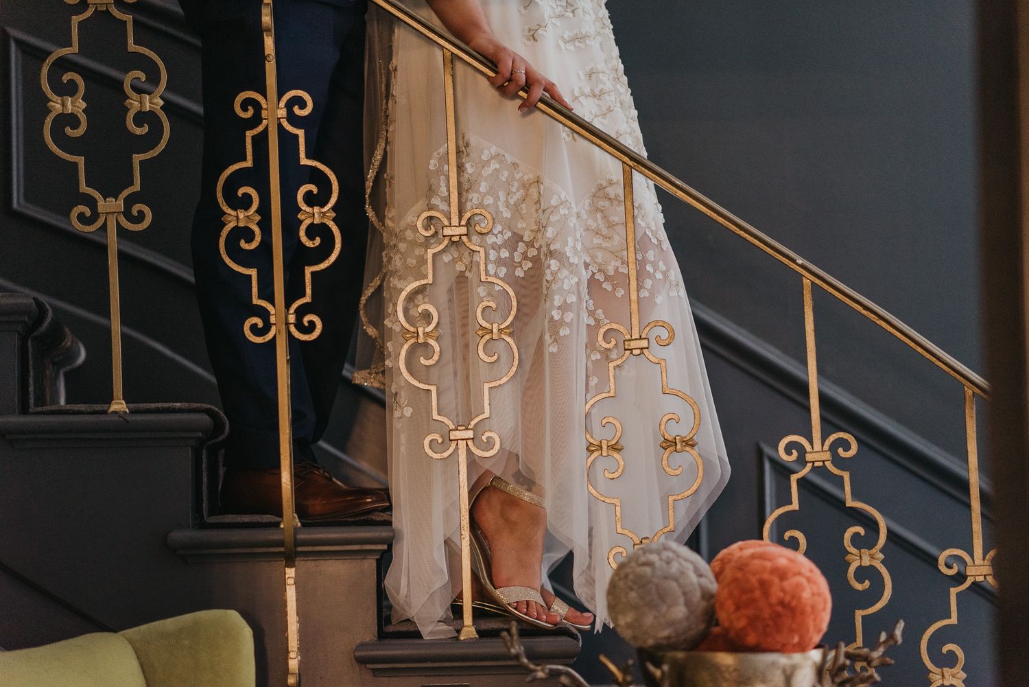 Detail shot of ornate golden staircase railing at wedding venue.