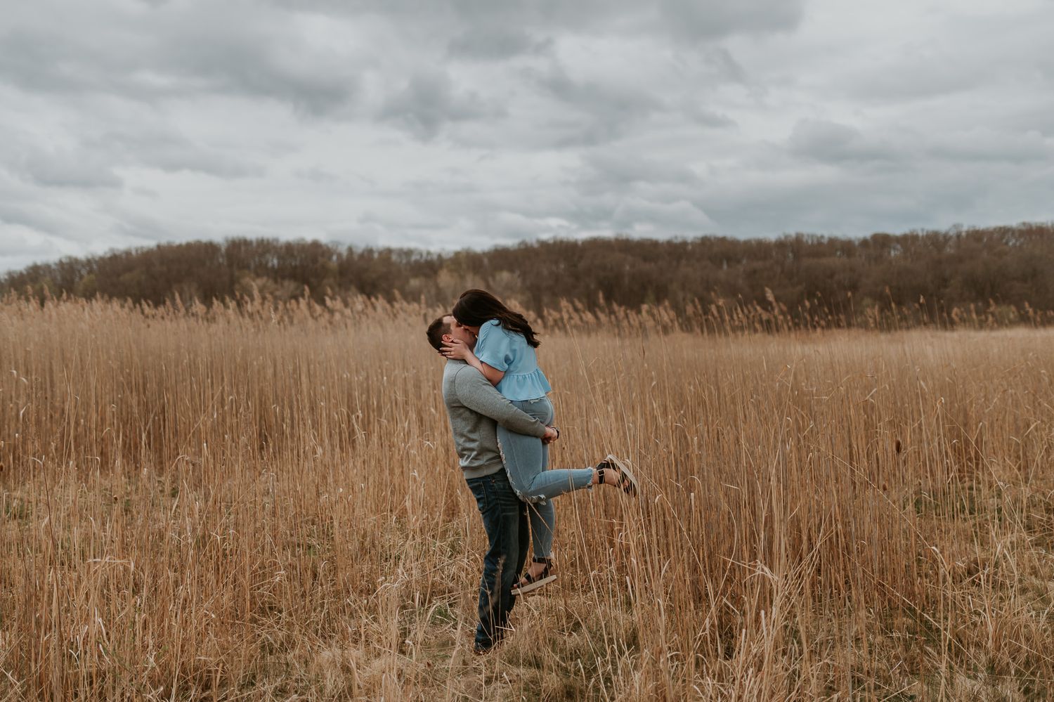 Dancing together in a tall grass field during an autumn engagement session.