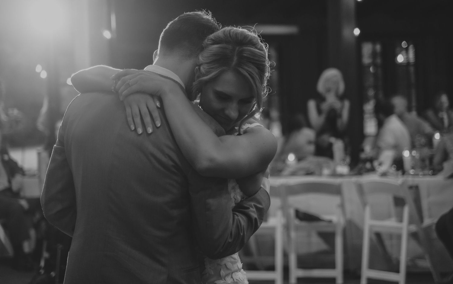 Black and white photo of wedding guests dancing and embracing during a reception celebration.
