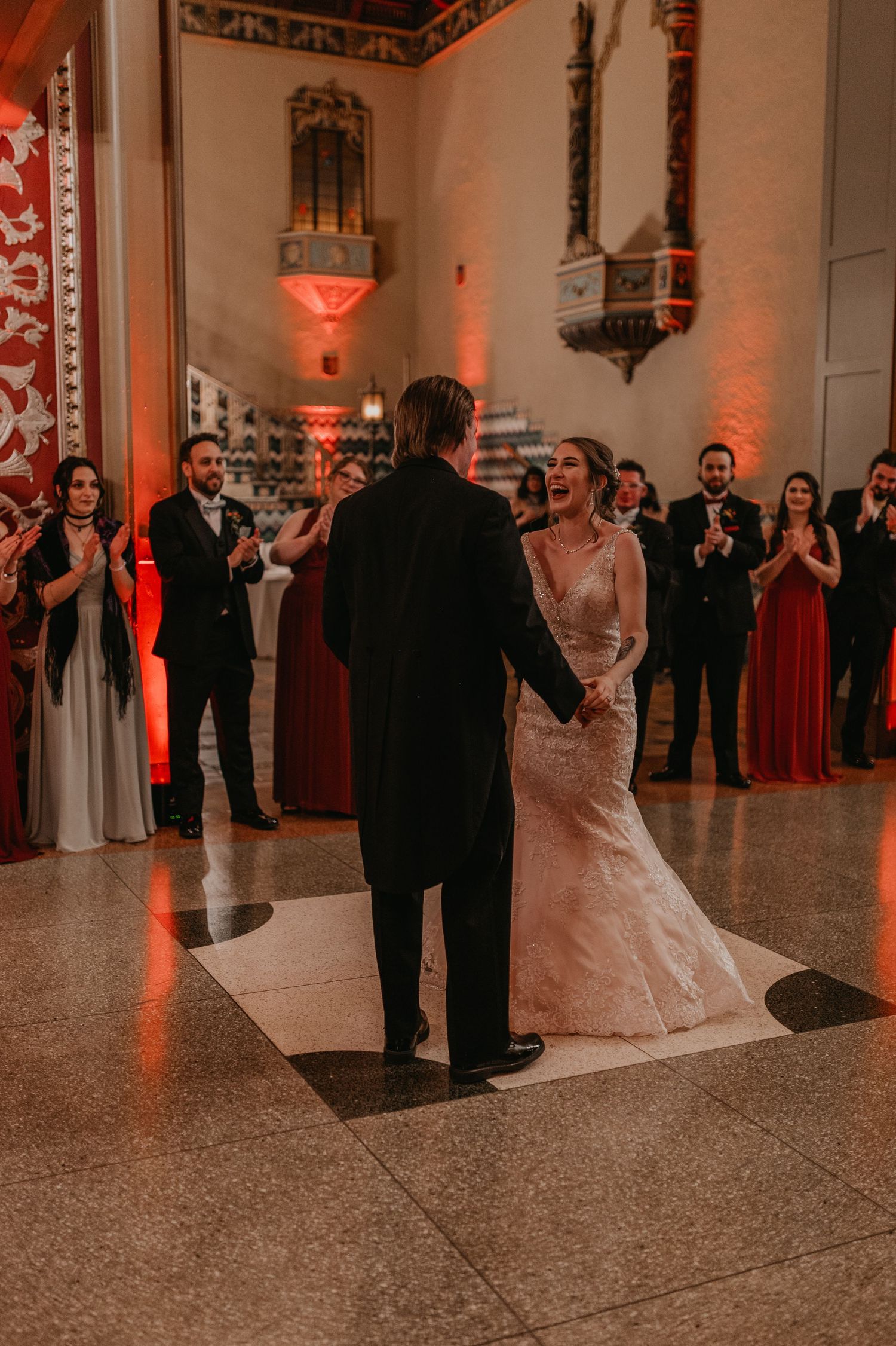 Couple shares their first dance surrounded by guests in an elegantly lit ballroom.