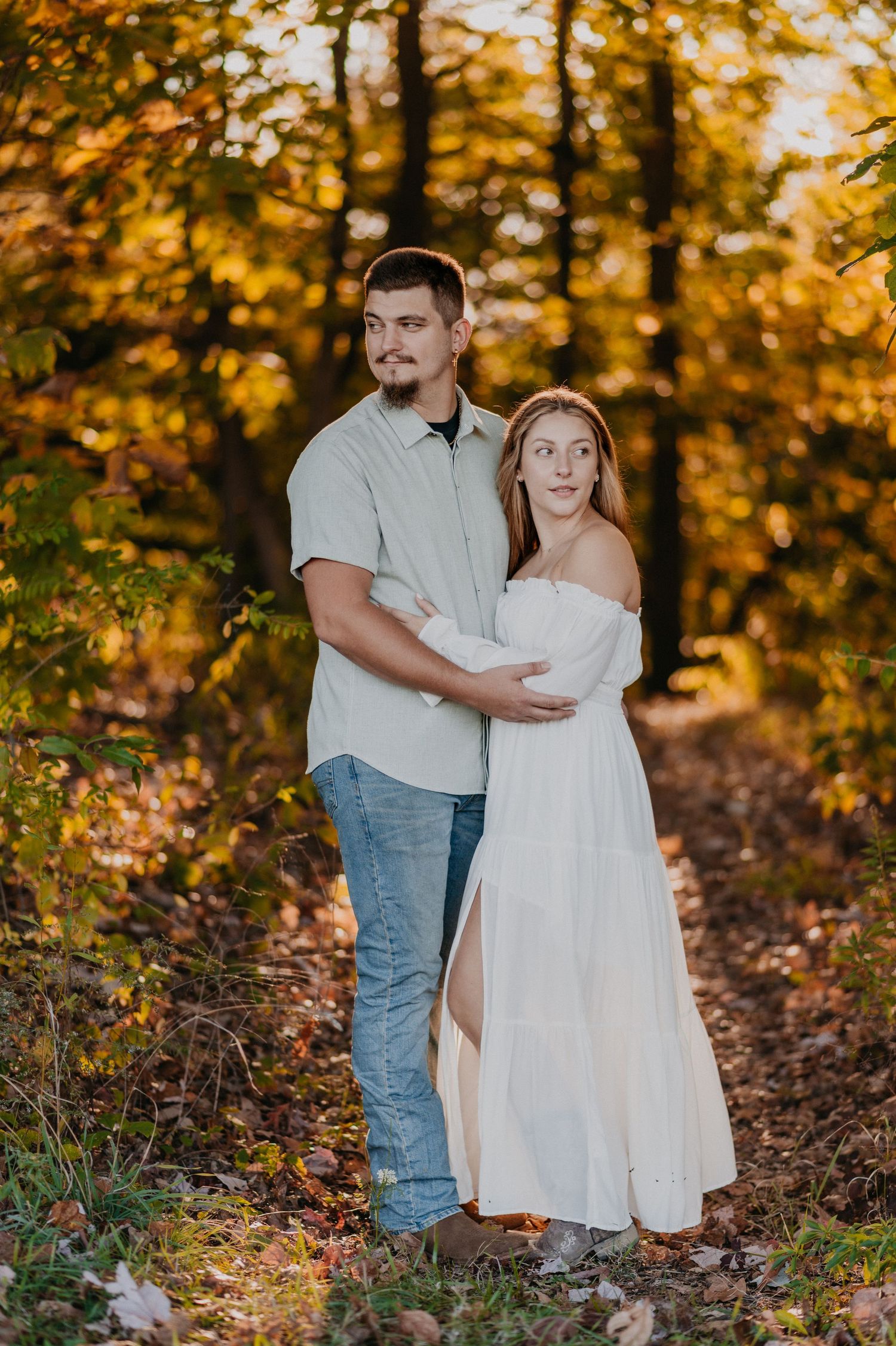 Autumn engagement photo session with couple among golden fall leaves.