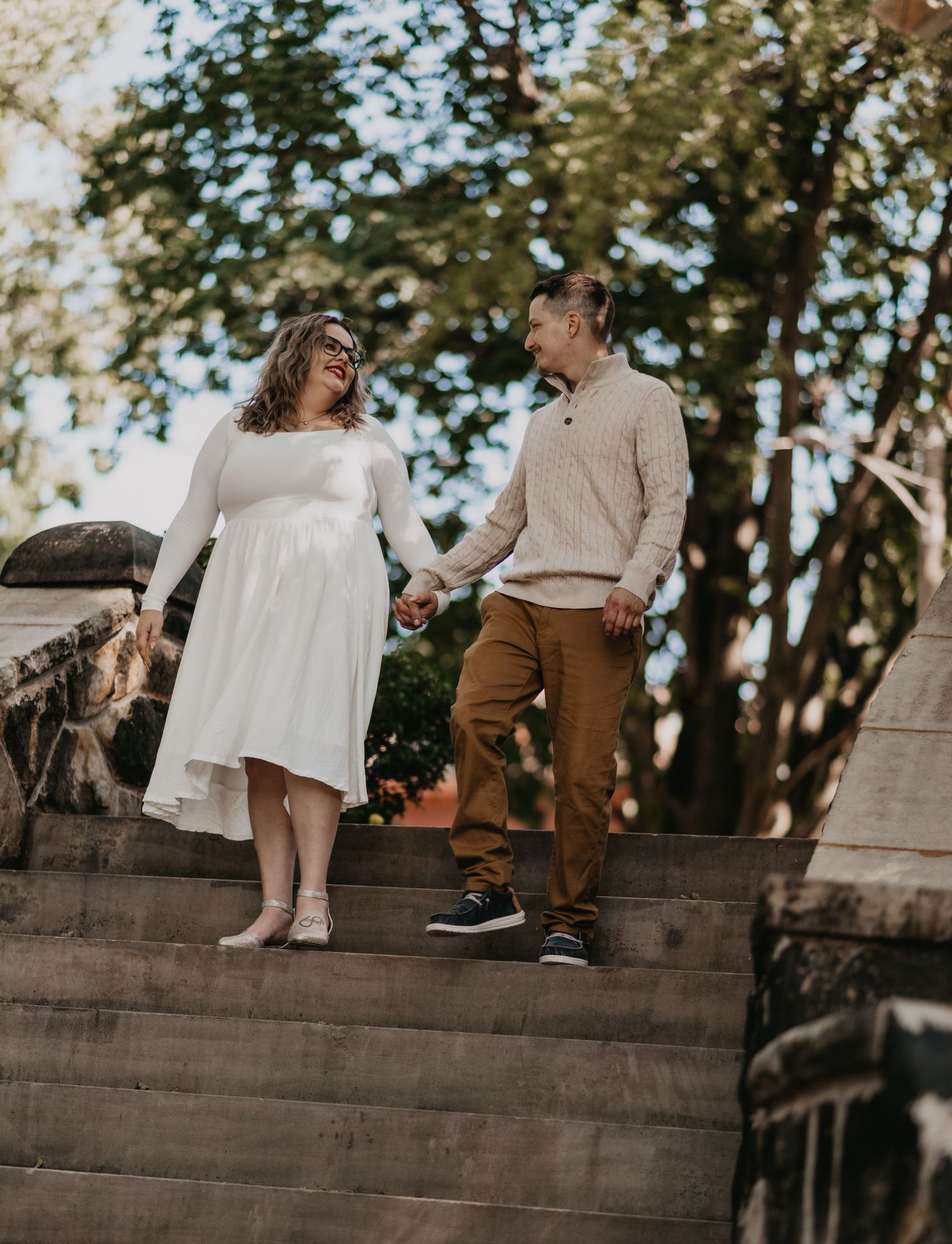 Couple sitting together on concrete steps in a romantic outdoor setting during golden hour.