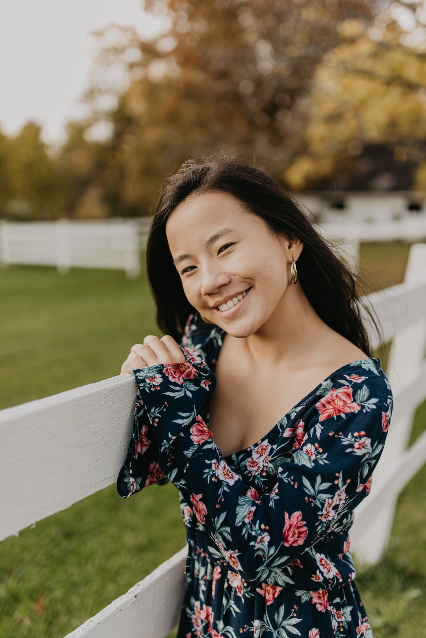 Someone in a dark floral dress poses expressively against a bright outdoor background.