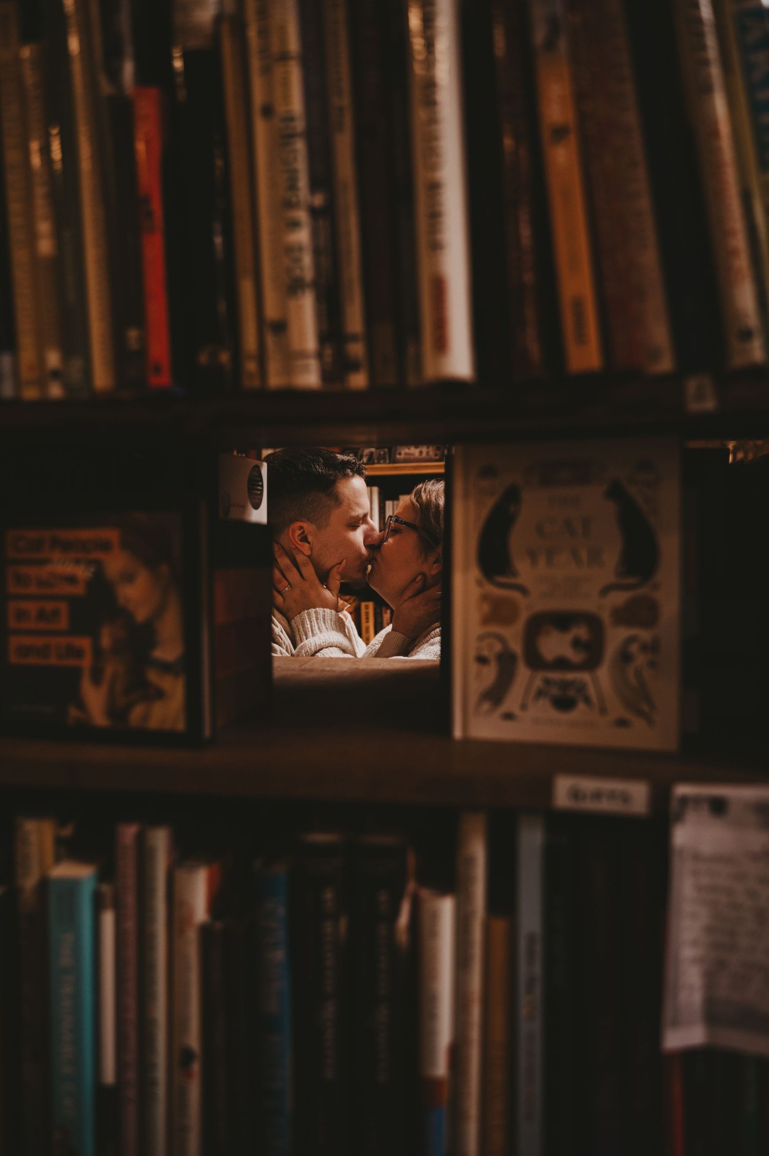 A cozy library interior with rows of books on wooden shelves in warm lighting.