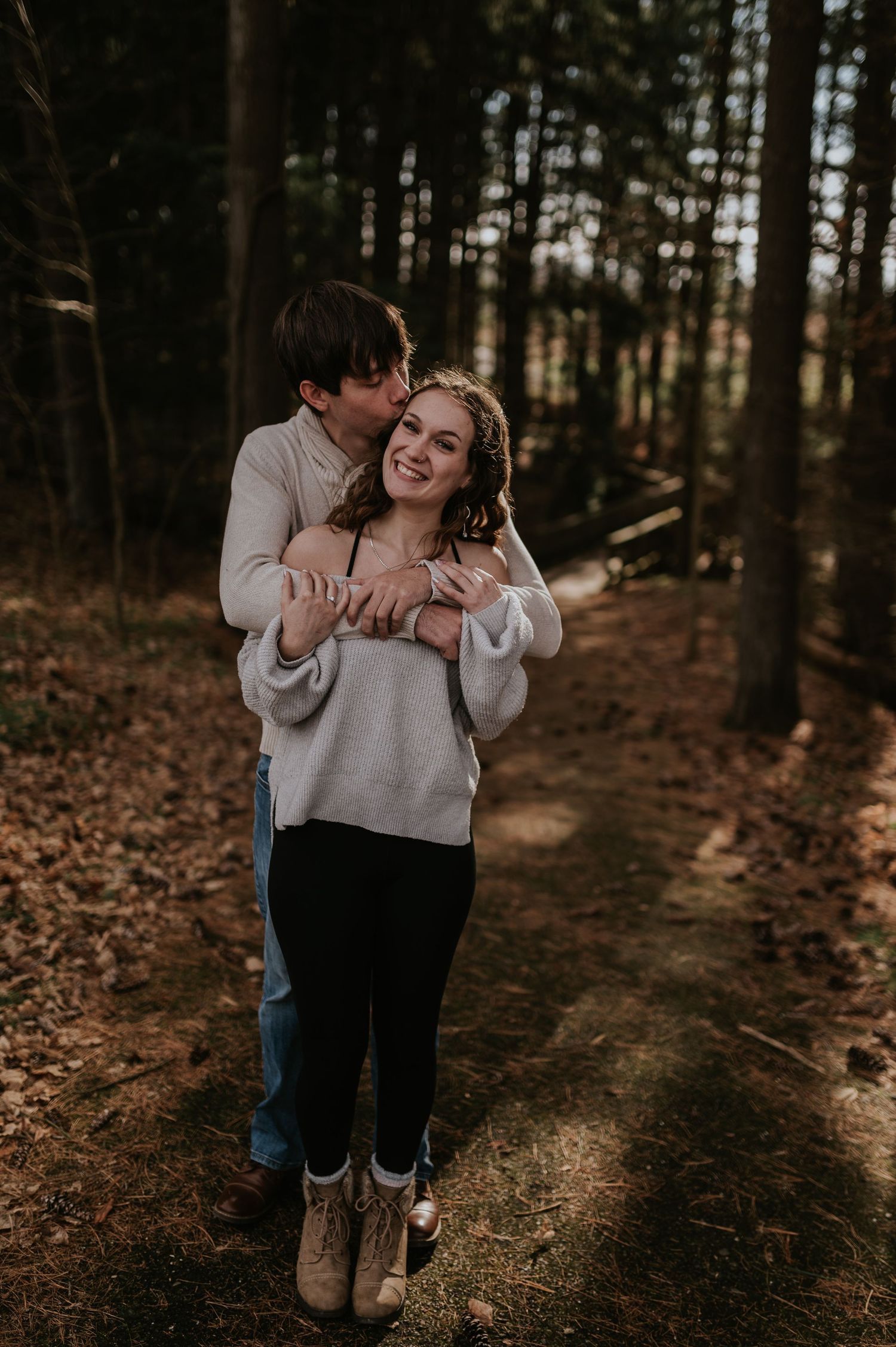 Couple in casual attire sharing a romantic moment on a forest trail.