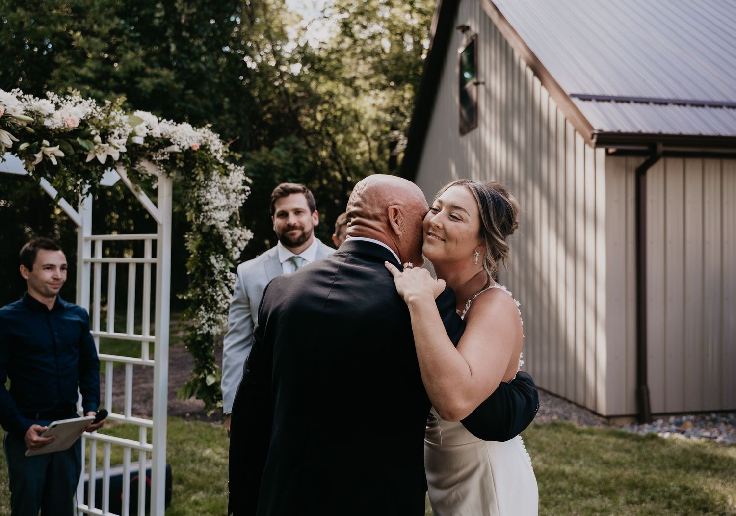 A couple sharing an intimate moment during their wedding ceremony on a sunny day outside a white building.