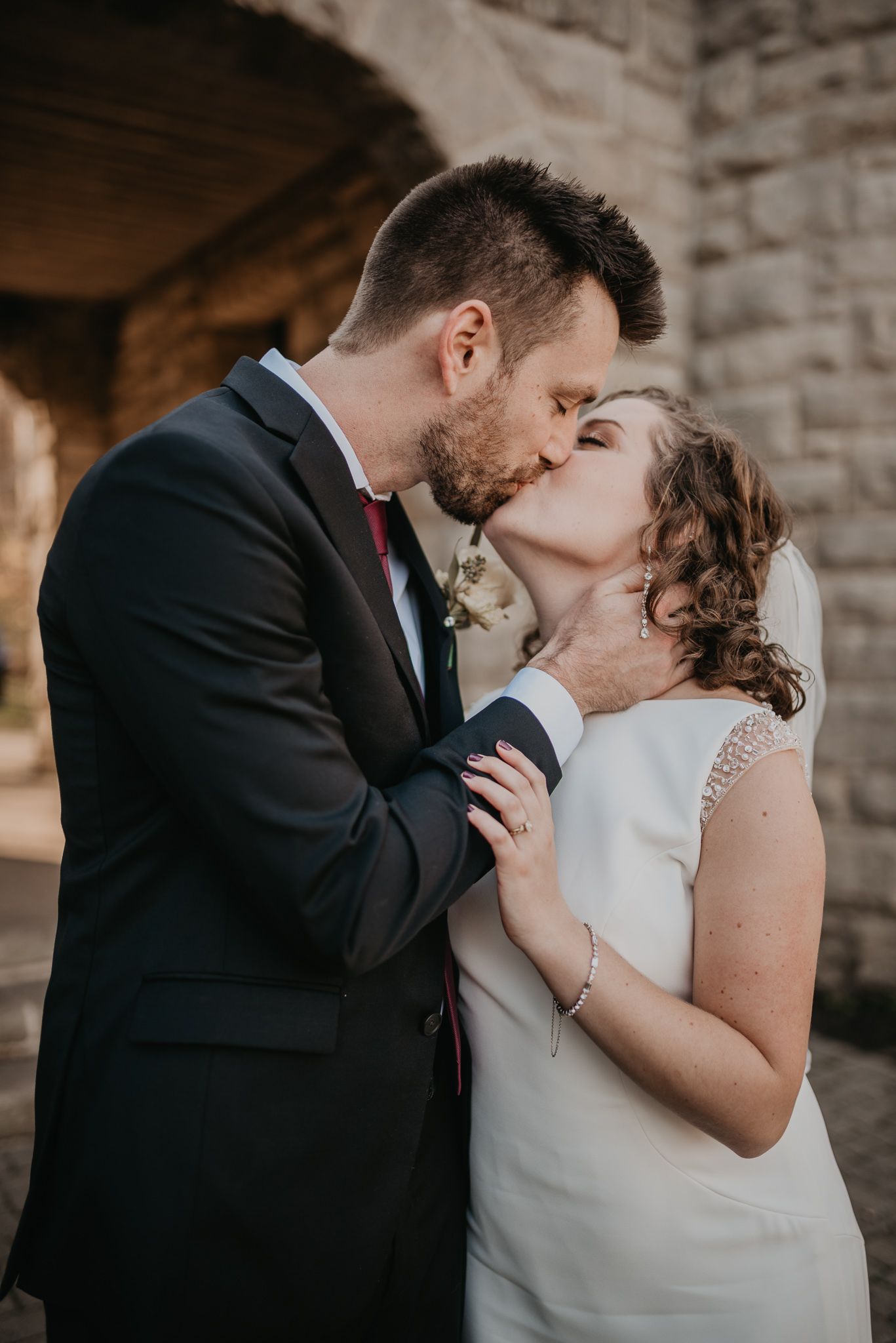 Intimate wedding portraits showing romantic moments between couple against stone wall backdrop.