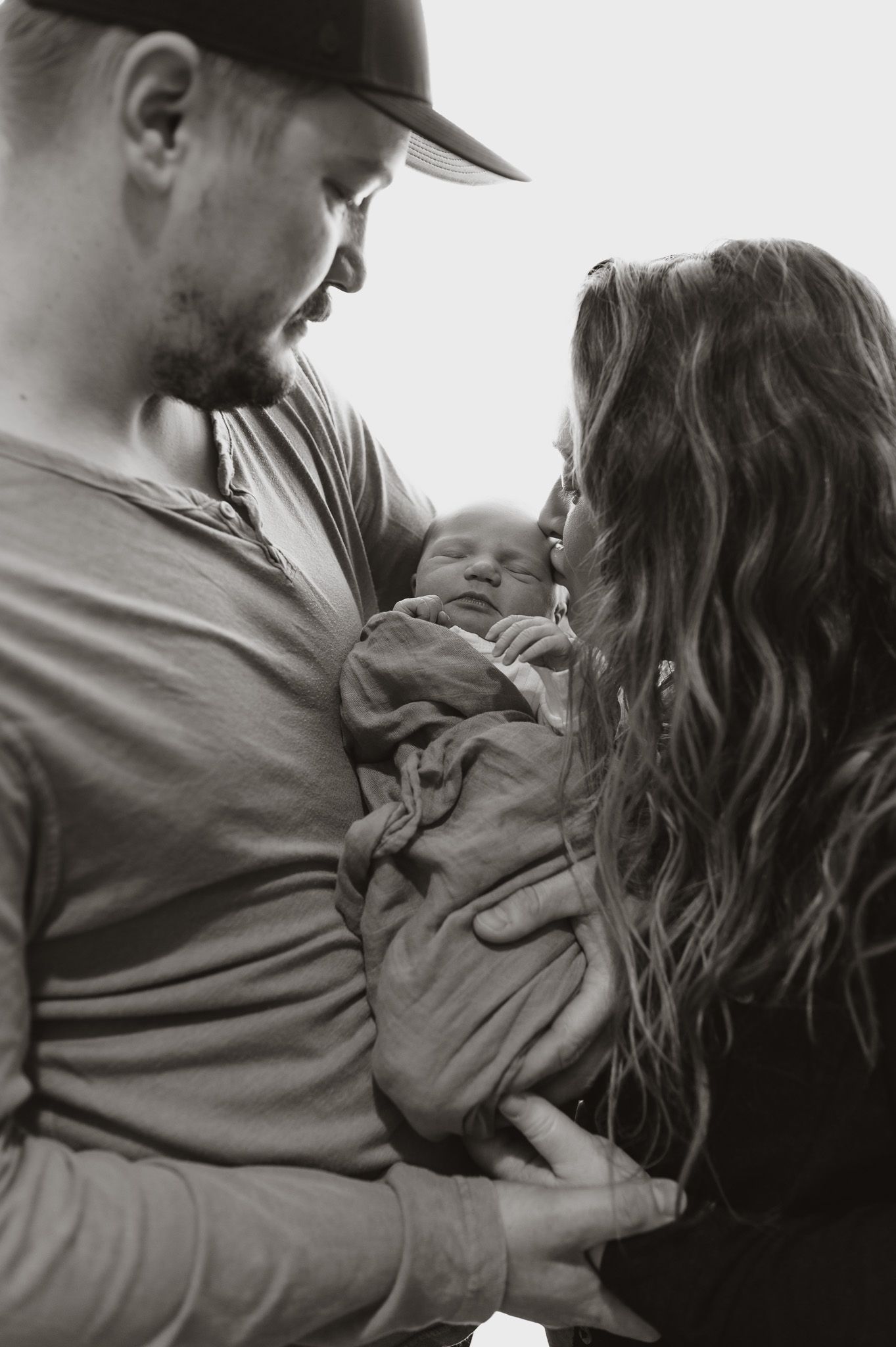 An intimate black and white family portrait showing tender moments with a newborn.