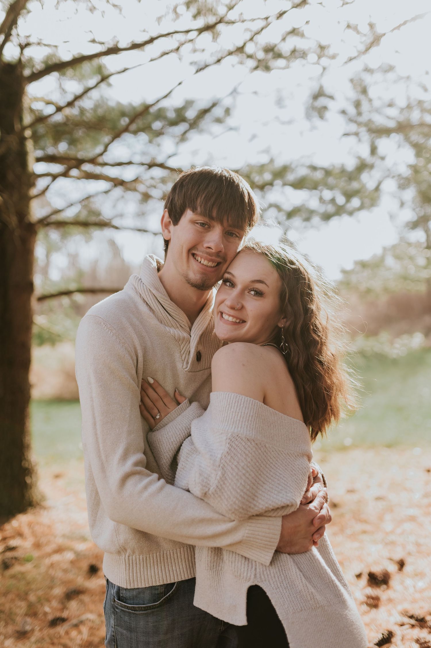 A sweet candid moment between a couple in cream sweaters during their engagement photos.
