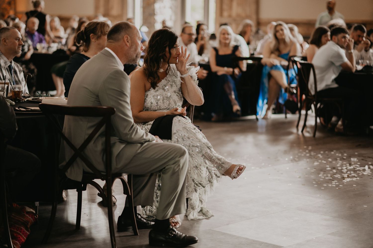 A wedding reception venue with guests seated at tables while a couple dances in a romantic setting.