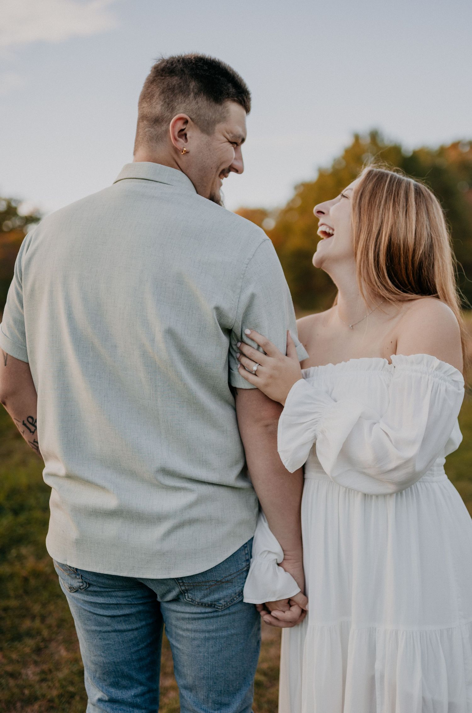 Couple in coordinating white and grey outfits share loving moment outdoors.