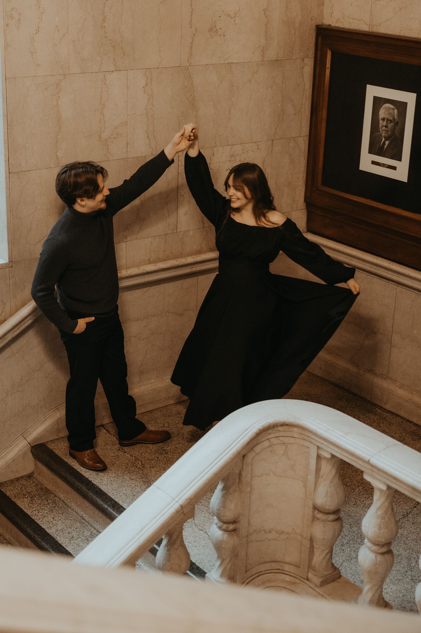 A series of four photos showing someone in black clothing climbing up marble stairs and interacting with artwork on a wall.