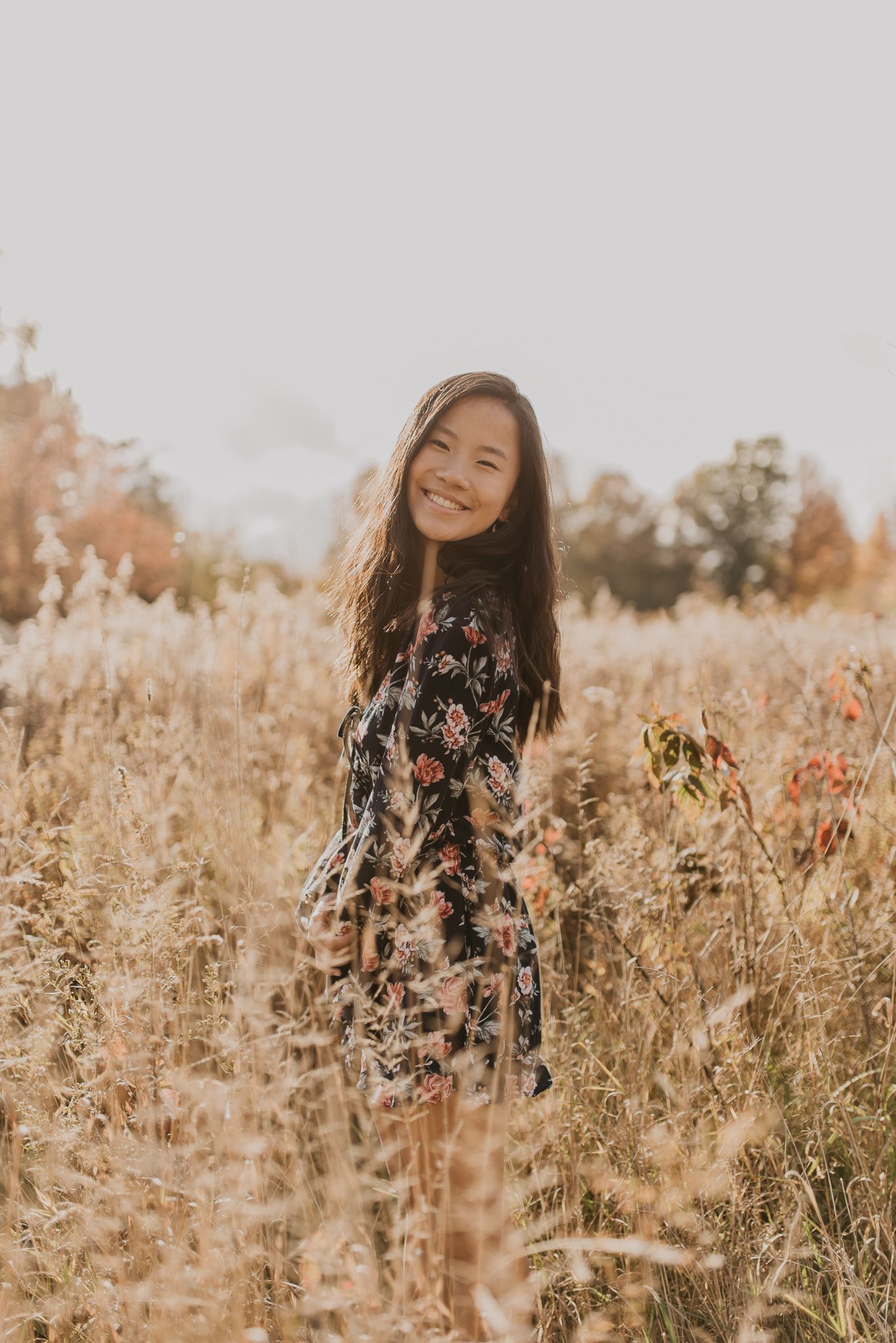 Candid portrait session in fall meadow with person wearing navy floral dress and natural lighting.