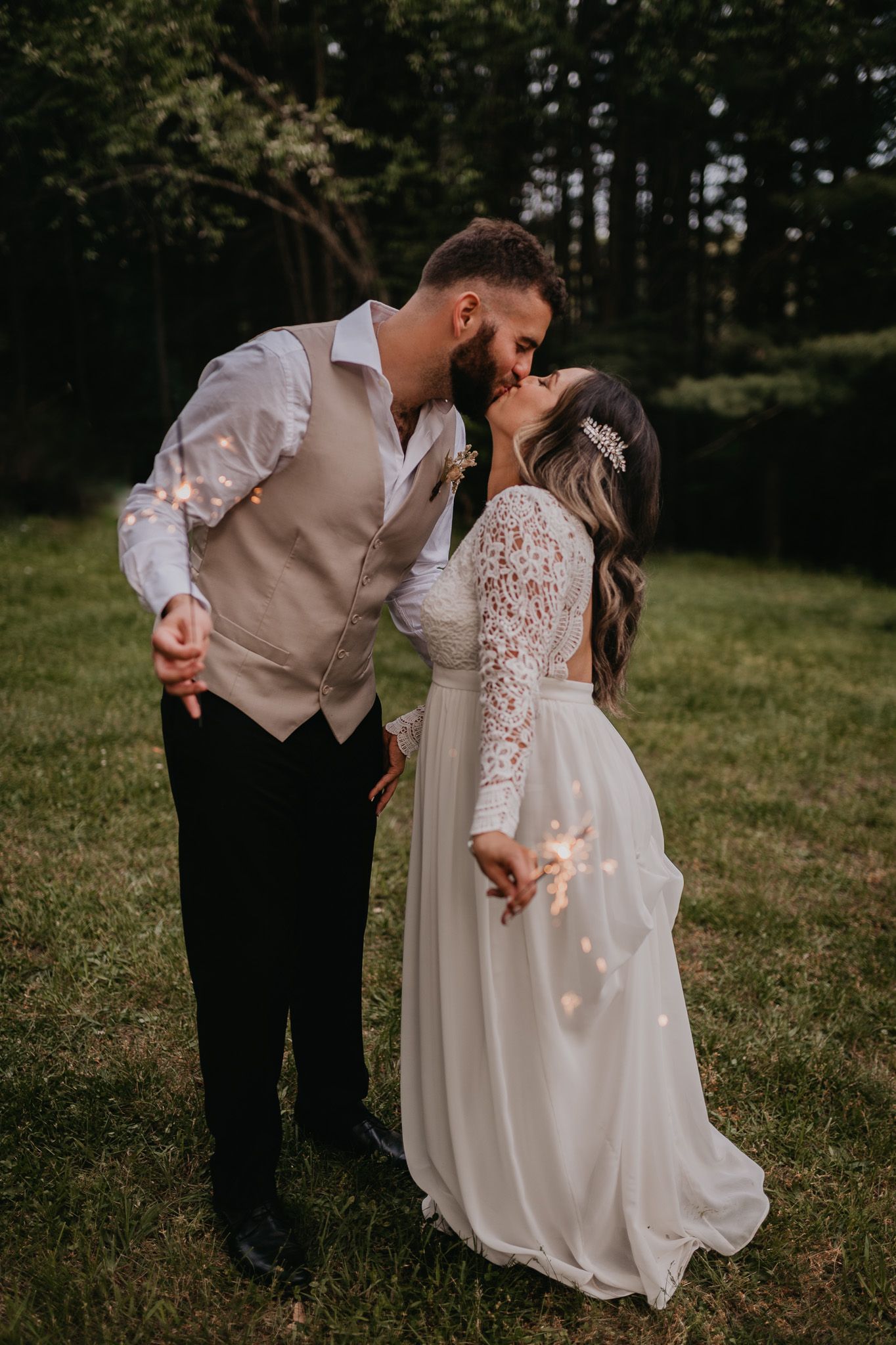 Romantic outdoor wedding photo of couple kissing in a sun-lit field.