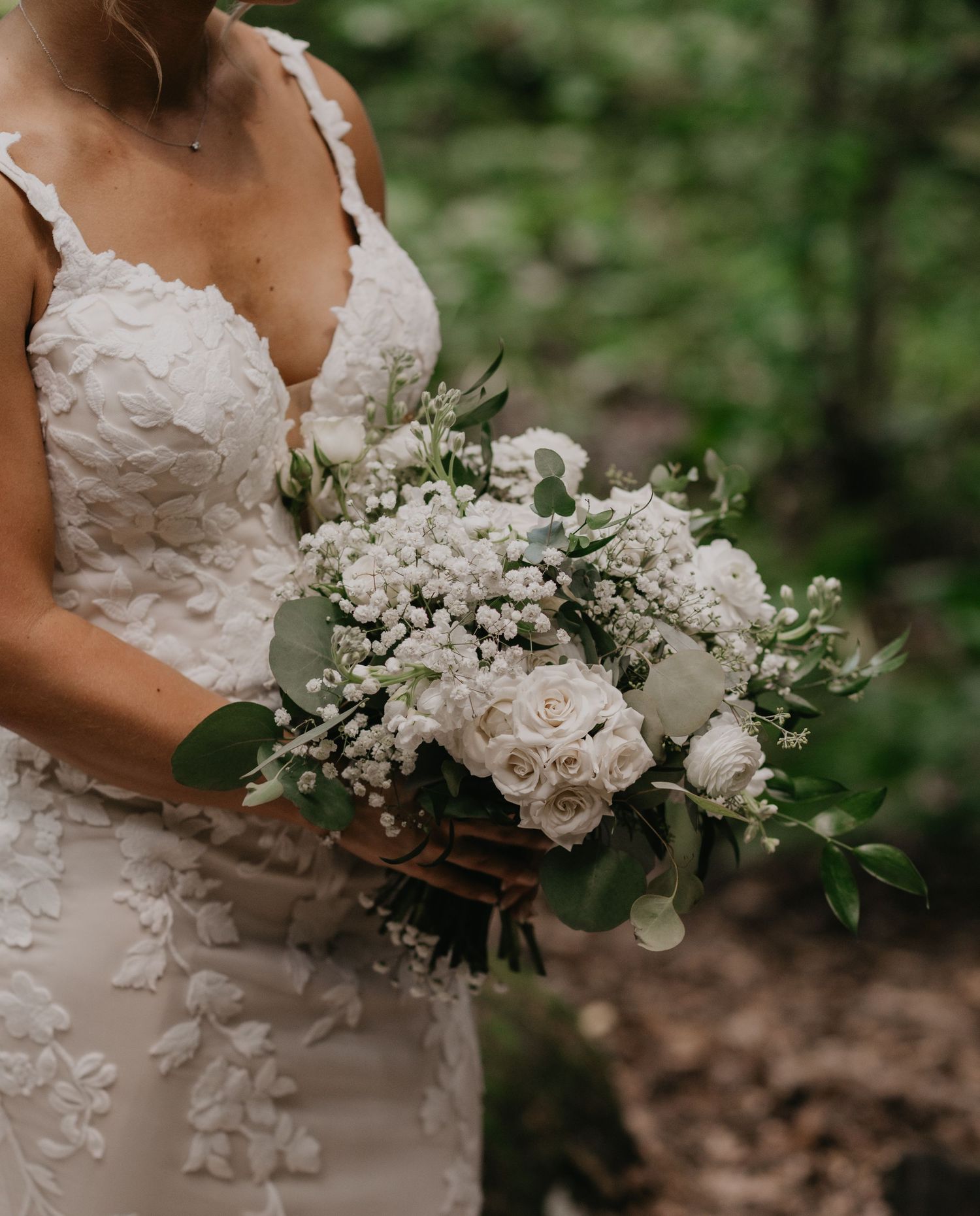 Elegant white bridal bouquets featuring roses and baby's breath flowers against a natural outdoor setting.