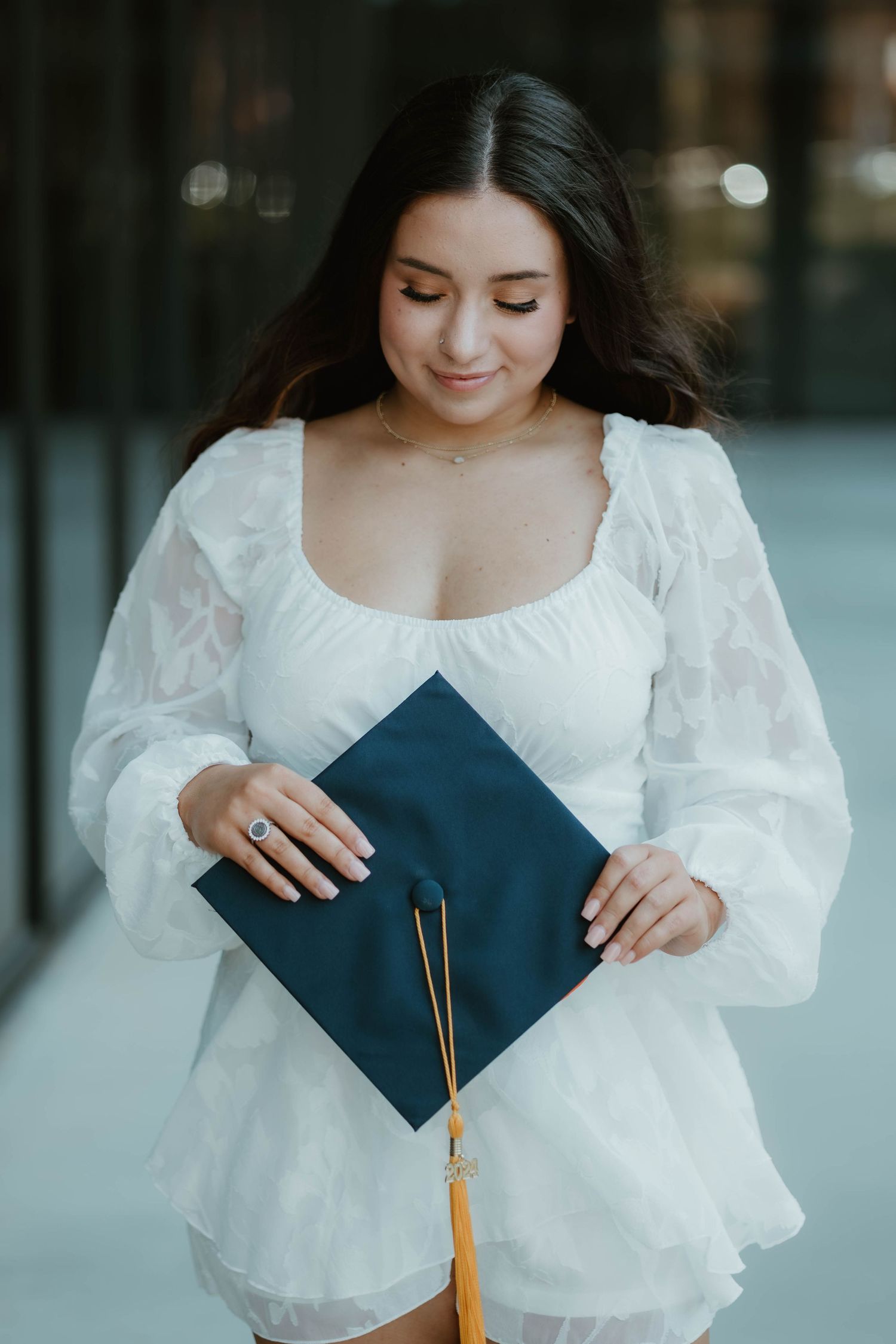 A graduate in a white dress holds a navy blue graduation cap with a gold tassel in a series of photos.