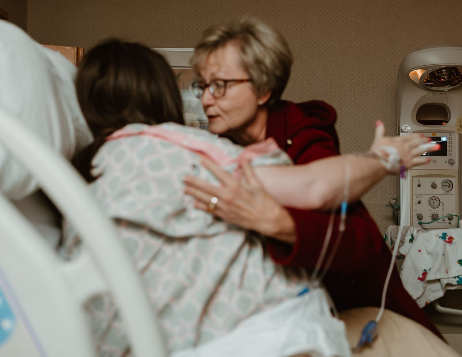 A healthcare professional assists a patient while monitoring medical equipment in a hospital setting.