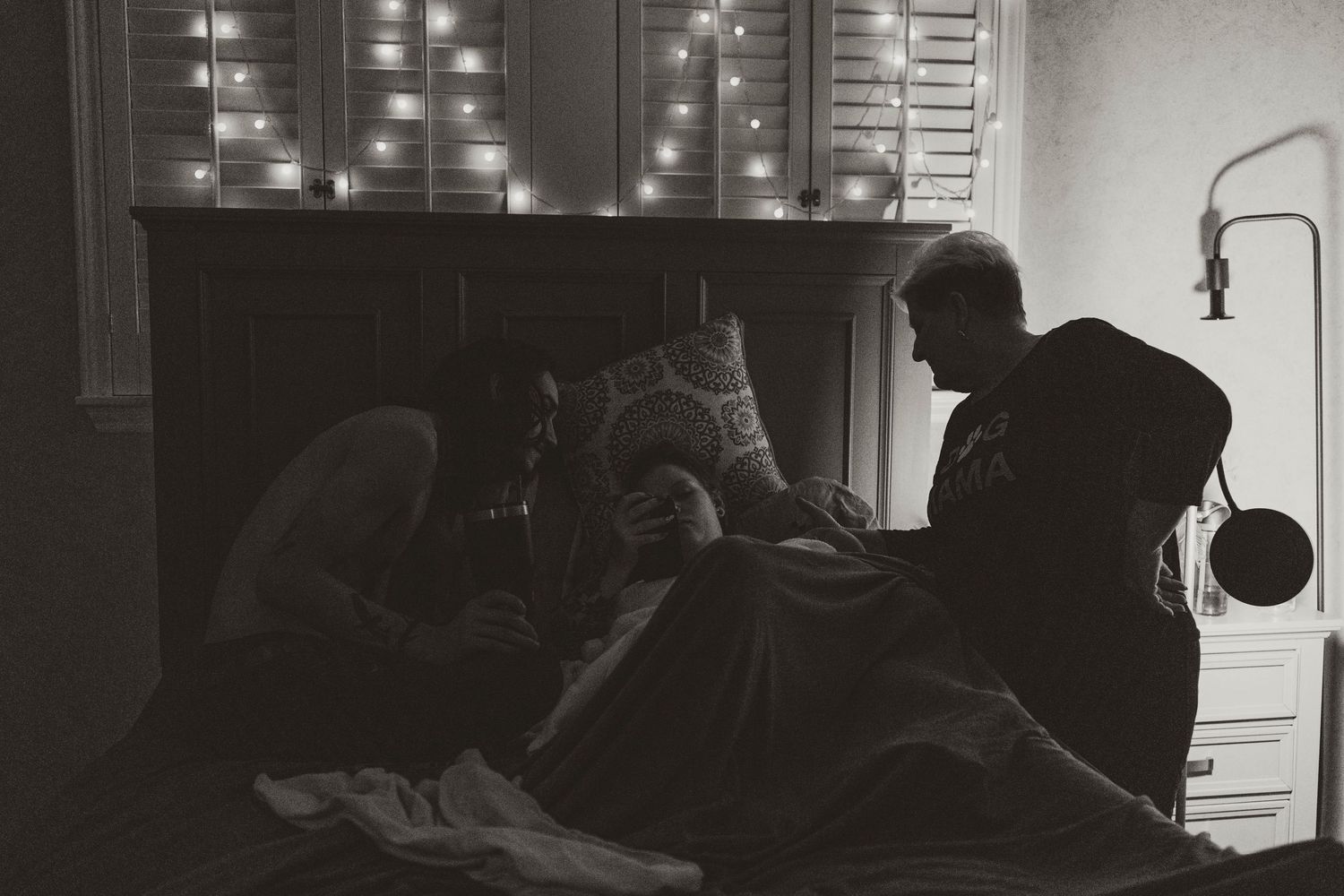Black and white photograph of medical professionals working in a dimly lit operating room with surgical lights.