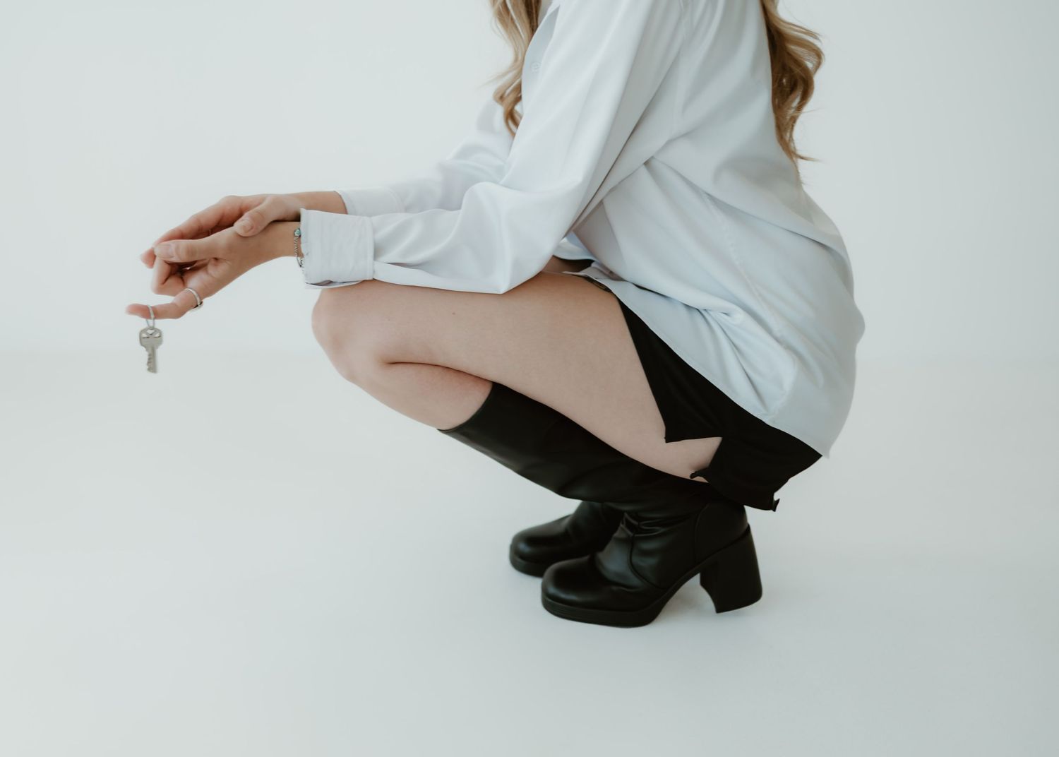Person in white shirt and black pants sits in dynamic poses against white backdrop and performs graceful movements.