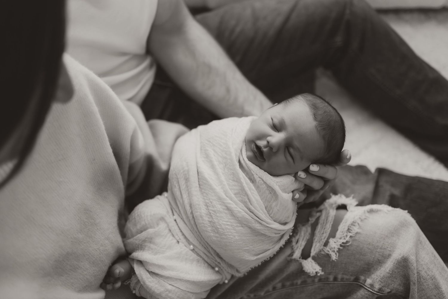 A series of black and white photographs showing a newborn baby being held and swaddled in a hospital setting.