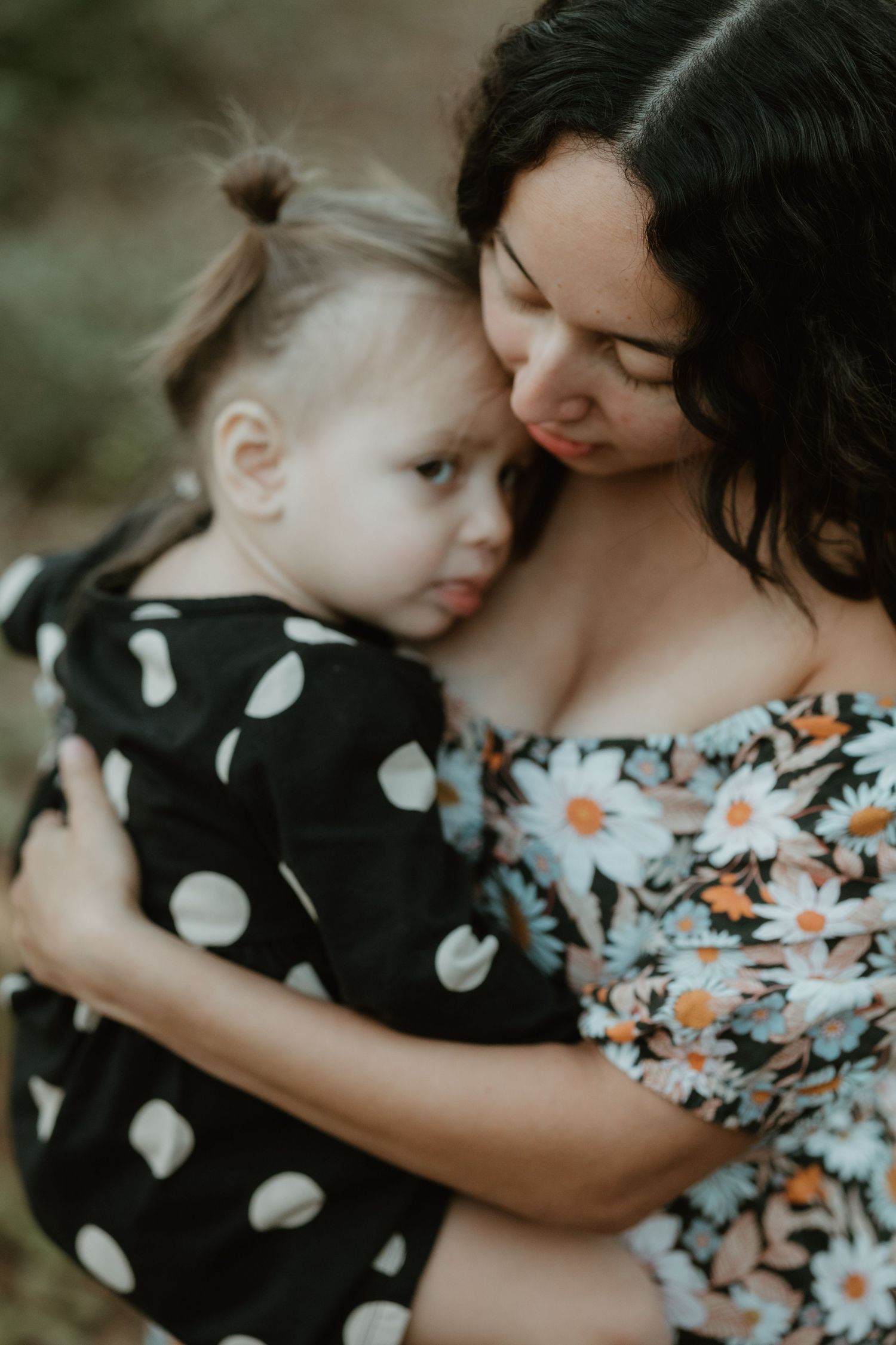 A tender embrace shows a floral dress and polka dot clothing in an intimate outdoor portrait.