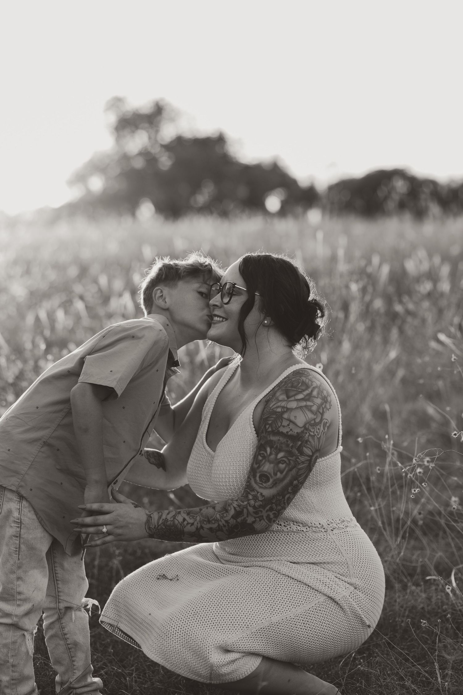 A romantic couple sharing tender moments in black and white while laying in a grassy meadow.