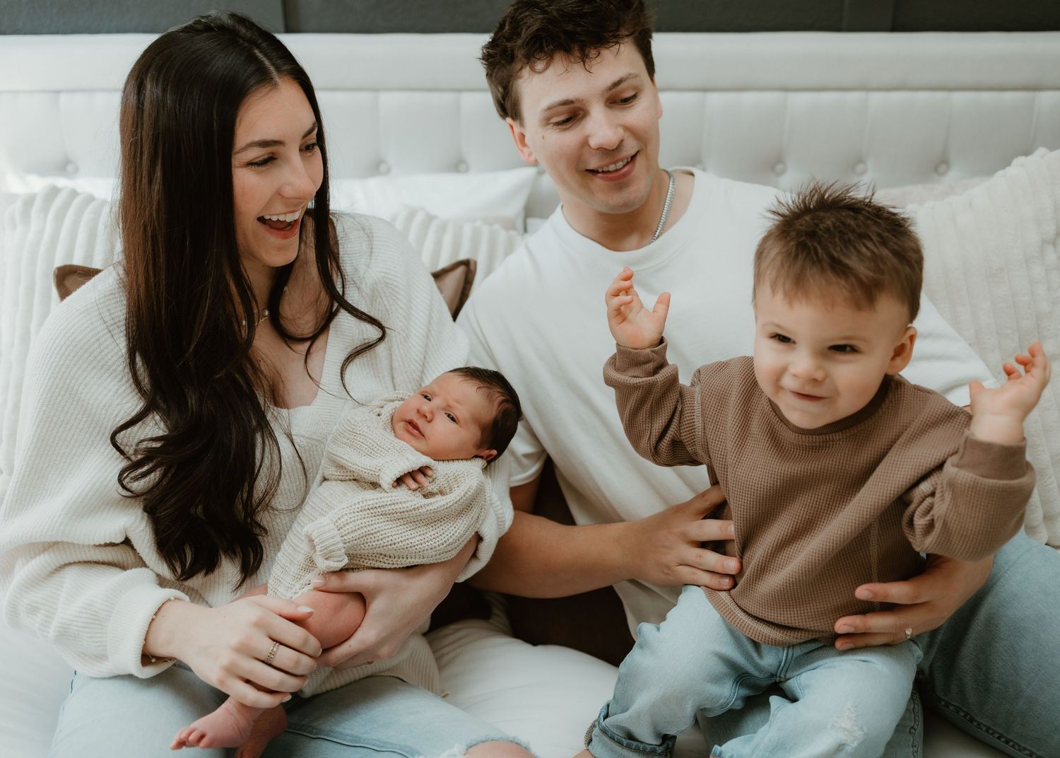 Family relaxing together on white couch sharing intimate moments and laughter in casual home setting.