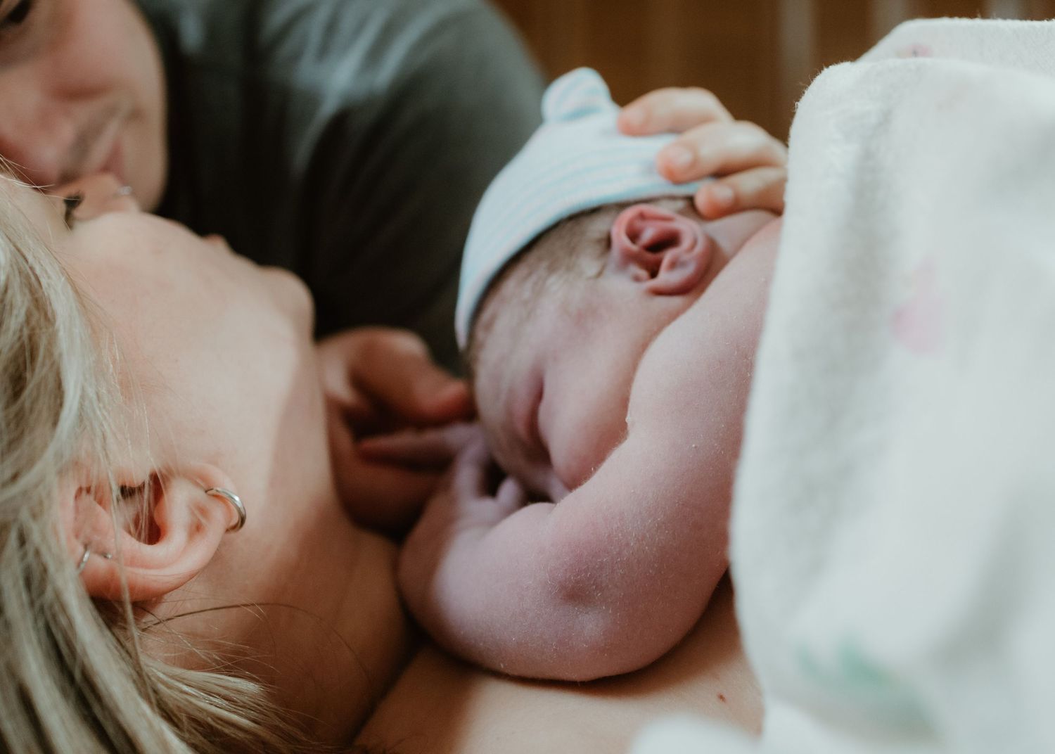 A newborn baby rests on their mothers chest immediately after birth in a hospital room.