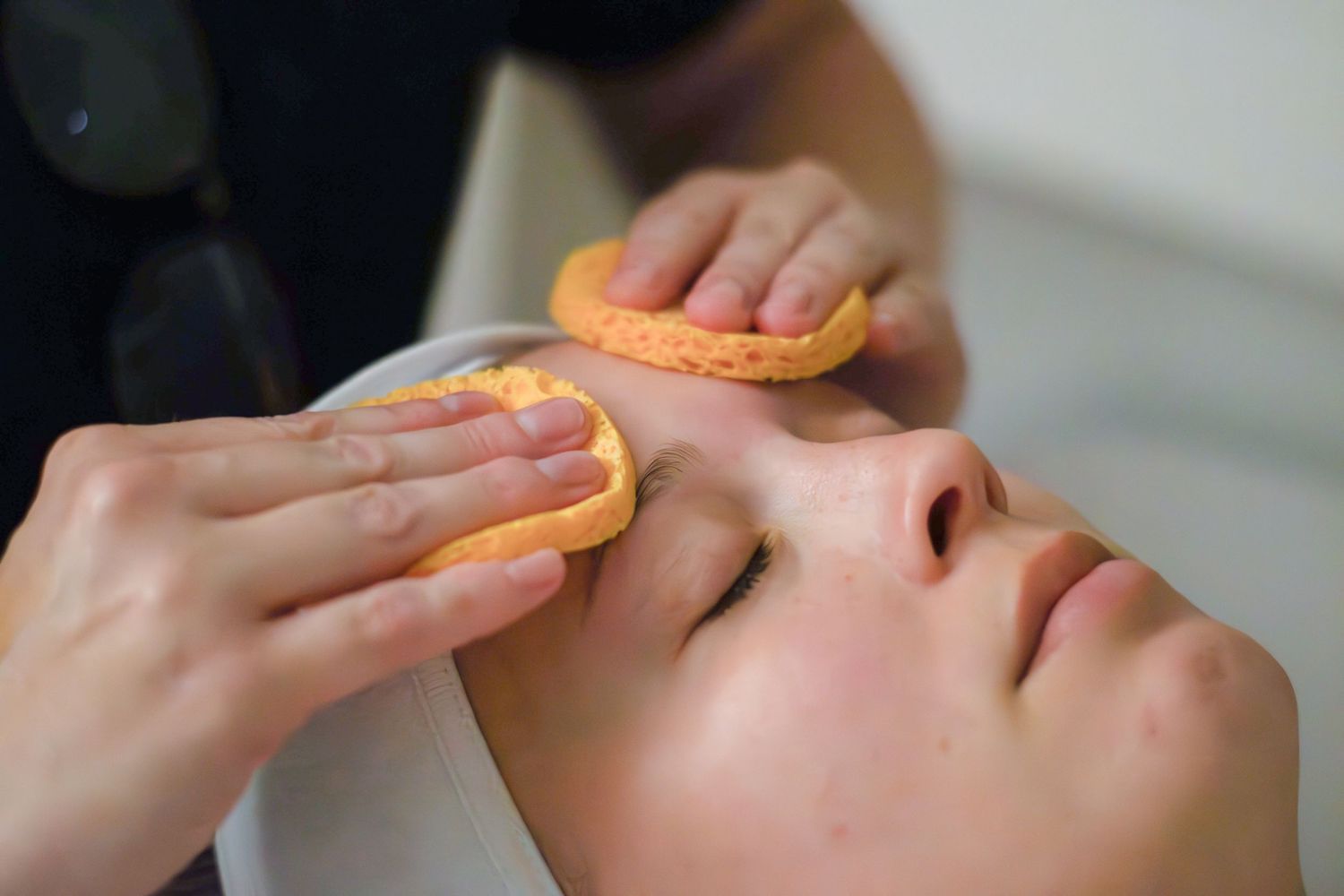 Close-up of hands performing facial massage techniques on a client during a professional spa treatment session.