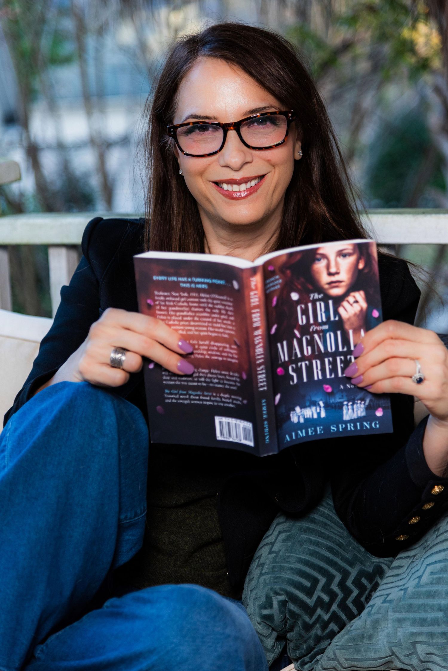 A series of photos showing someone reading a book while relaxing on a couch in a blue sweater.