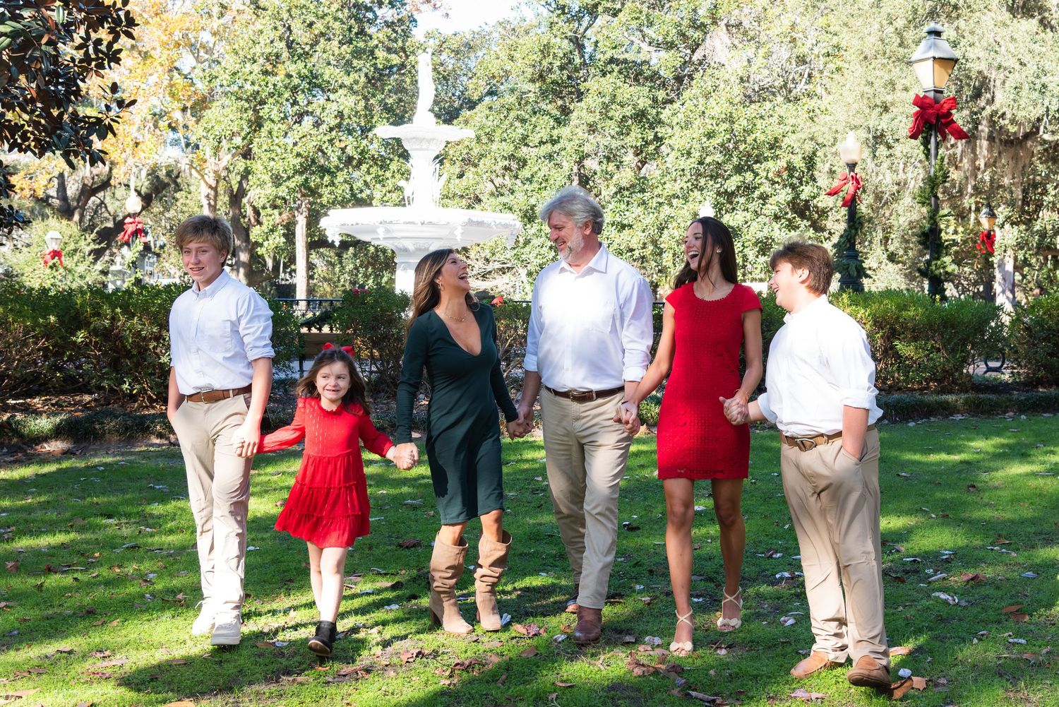 A group of people walking through a lush green garden setting in casual and semi-formal attire.