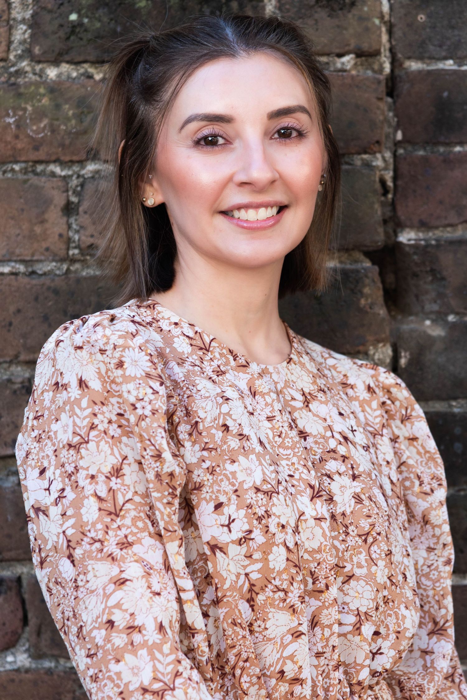 A series of portrait photos showing someone in a brown and white floral patterned dress against a brick wall background.