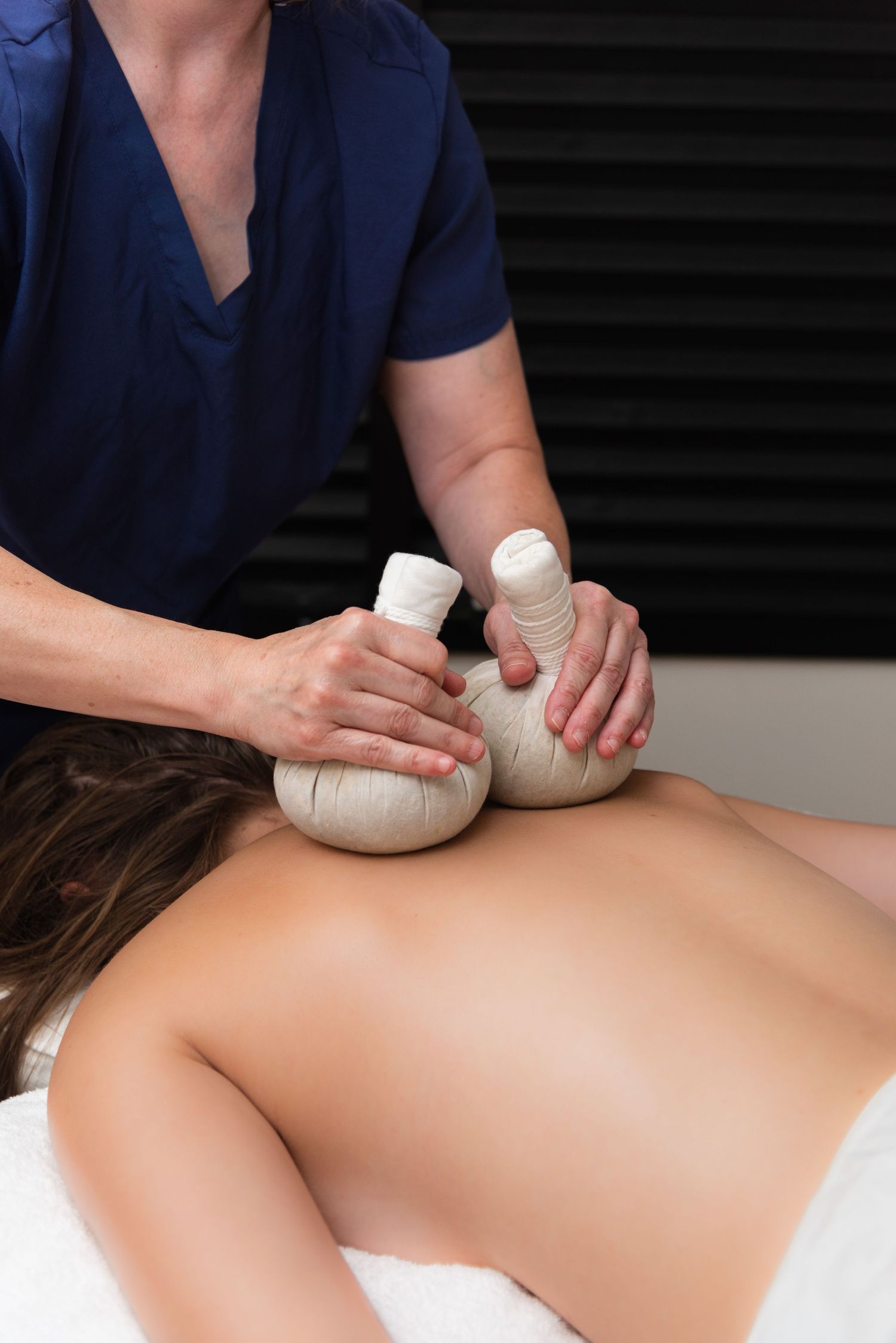 A massage therapist performs therapeutic massage techniques on a client's back using firm pressure and circular motions.