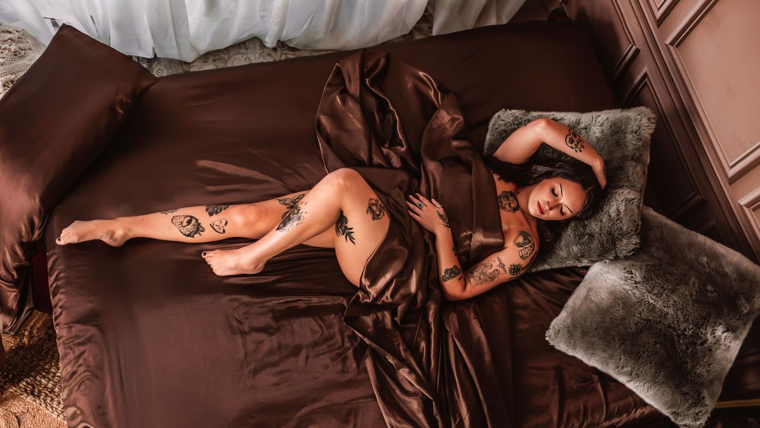 Indianapolis Indiana boudoir portrait of client laying on brown silk bedding with sheer curtains