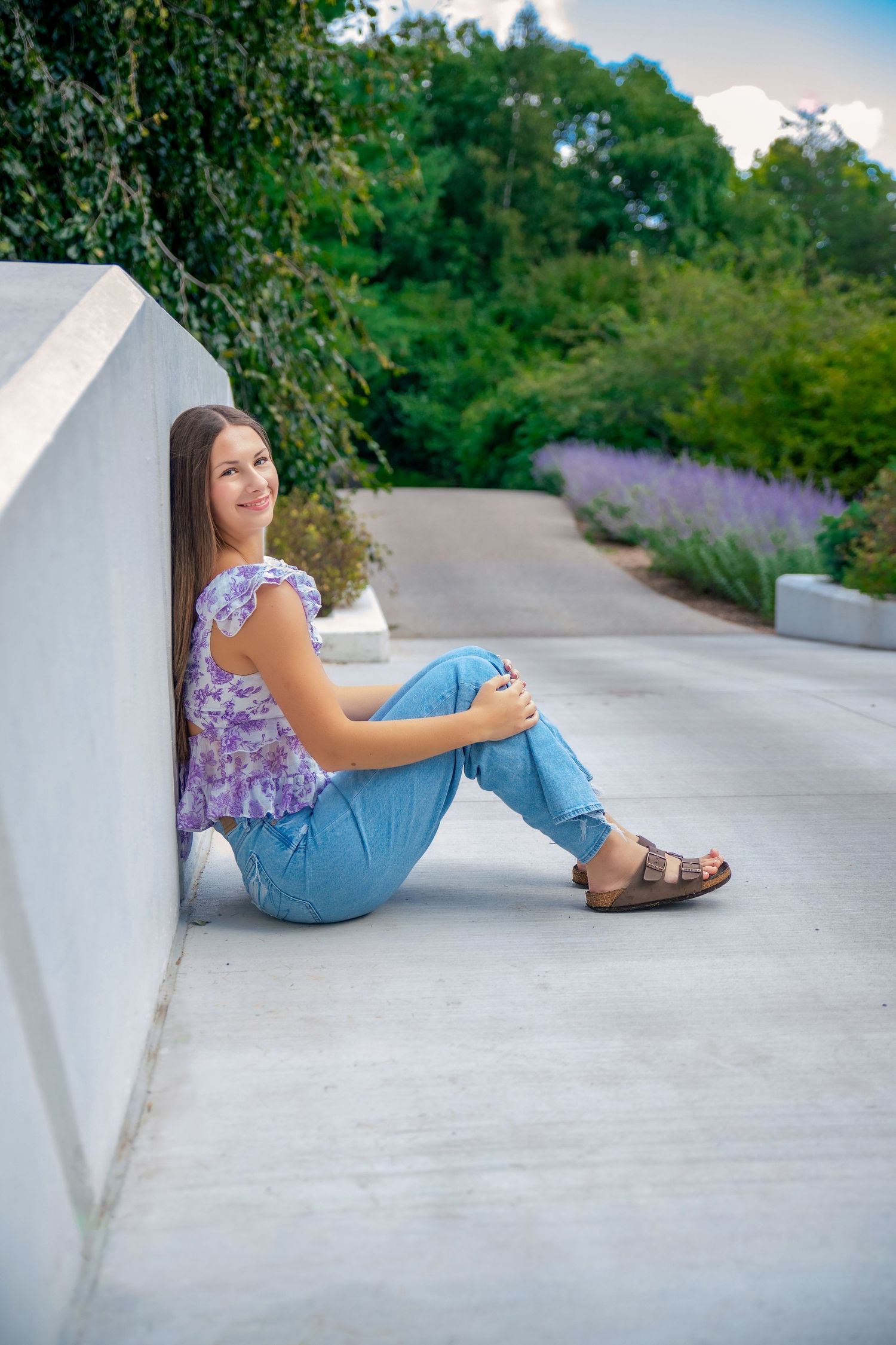 Casual outdoor portrait session along a white concrete wall on a summer day.