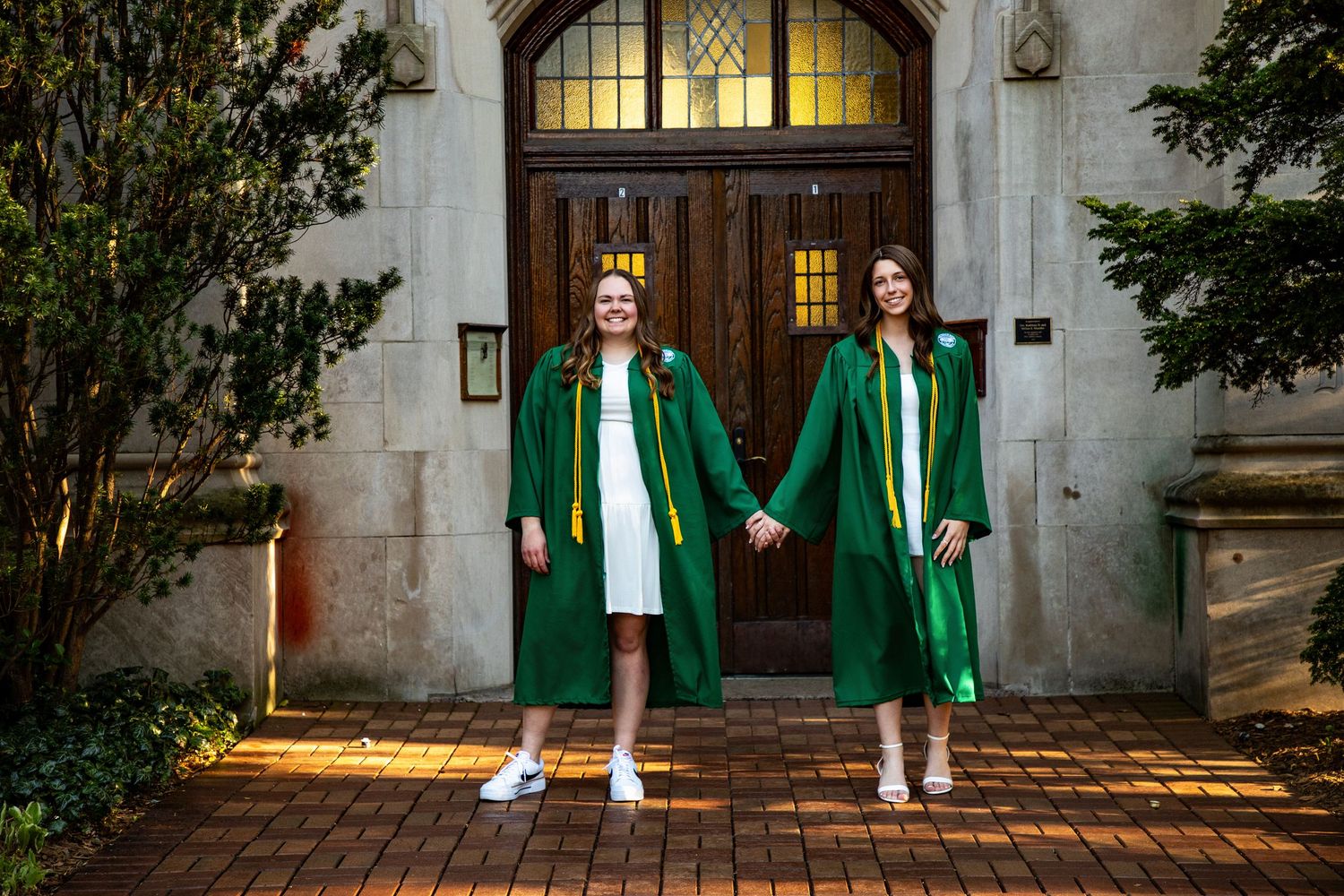 Graduation photos taken in front of historic building with green doors and stone architecture.