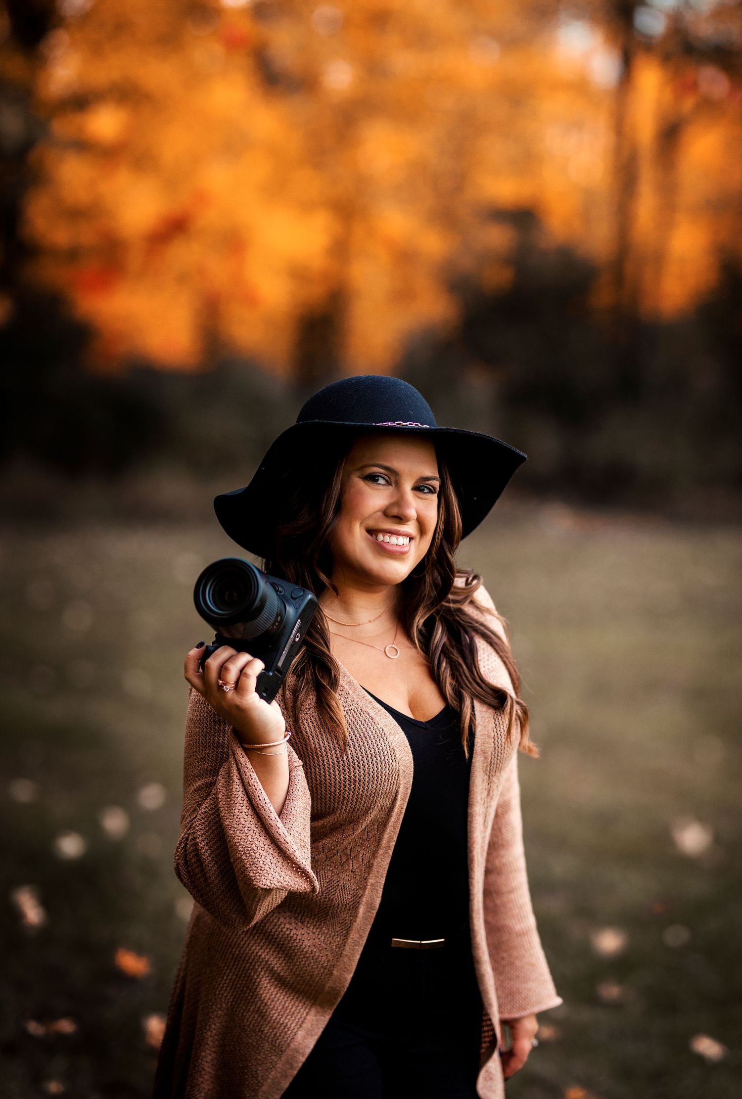 Autumn photography session with wide brim hat and camera against golden sunset.