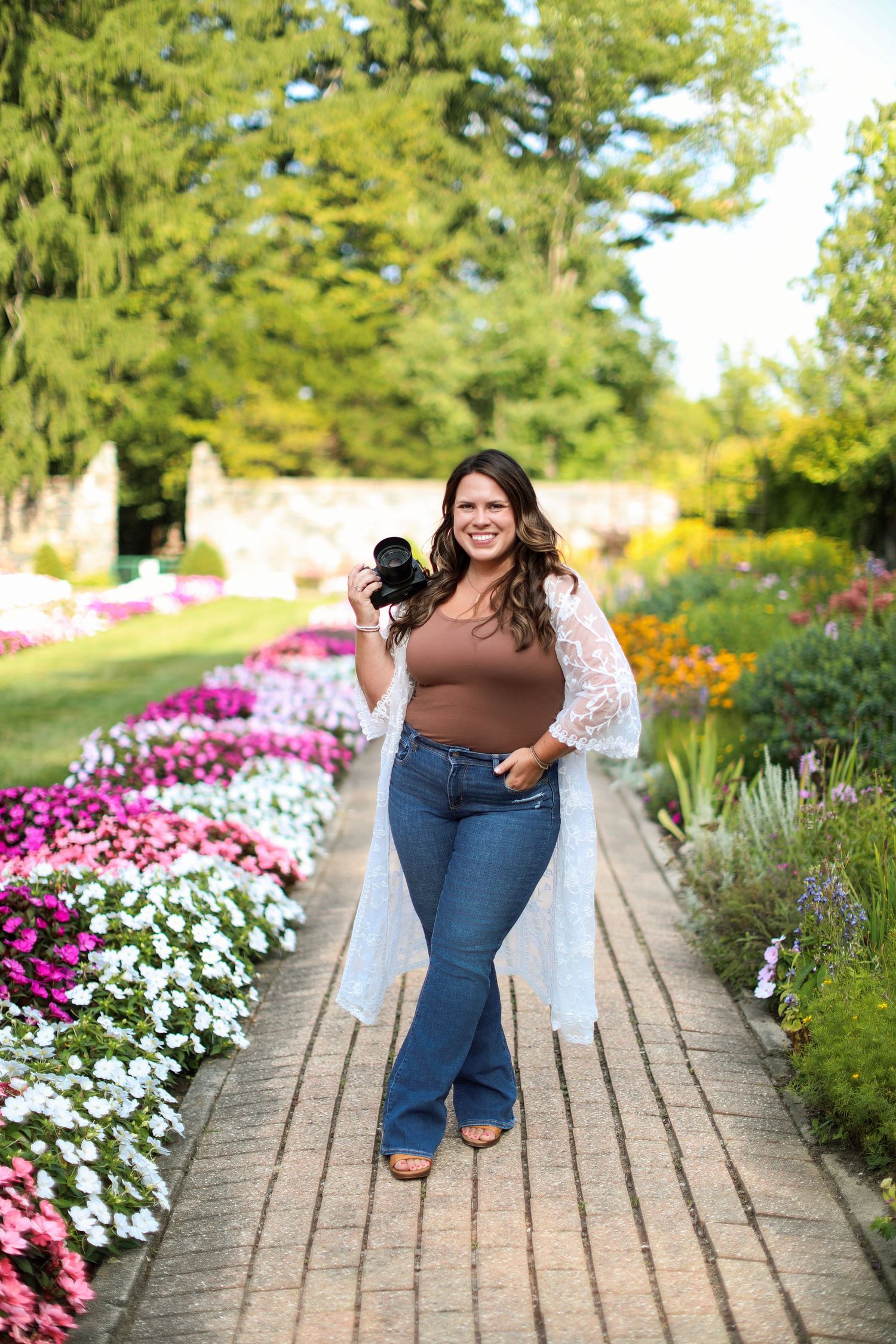 Garden photoshoot on brick path surrounded by pink and white flowers in summer.