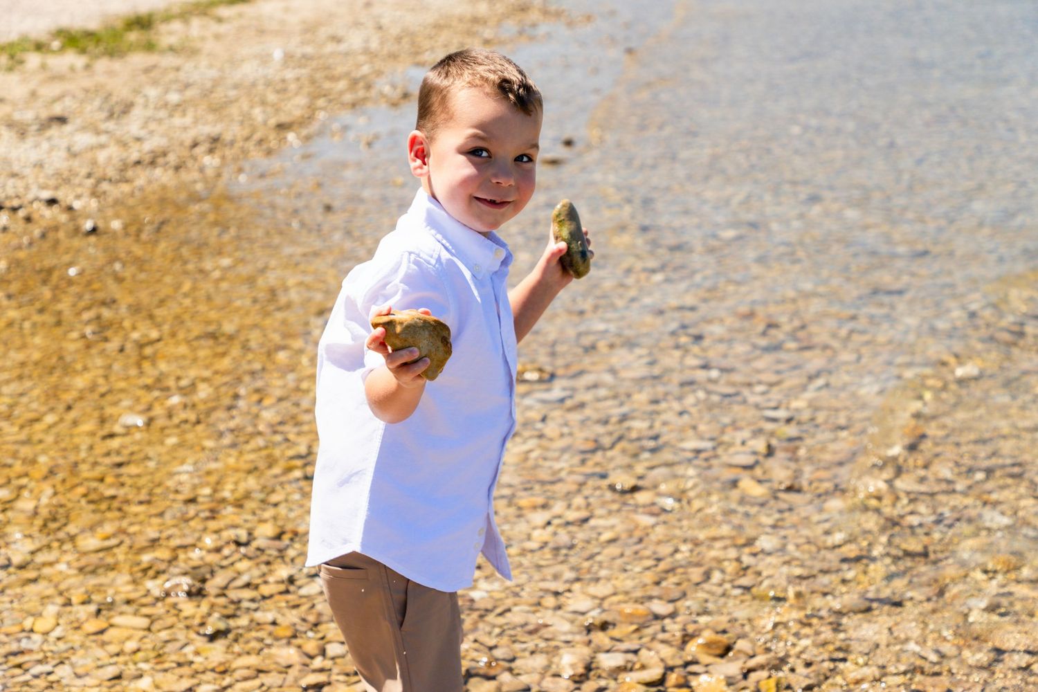 Child playing and walking on a rocky beach shoreline in summer.