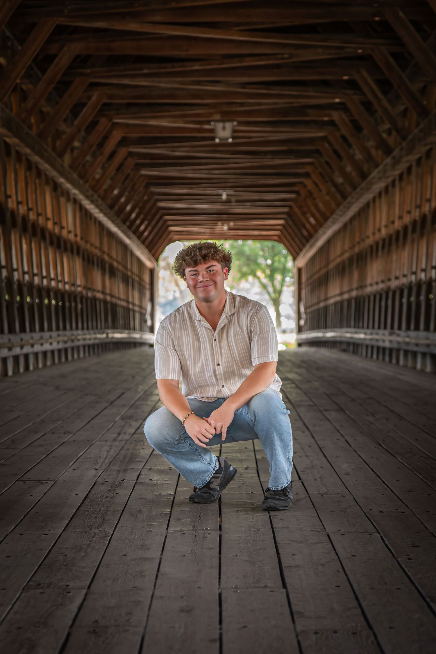 A portrait inside a wooden covered bridge with dramatic lighting and symmetrical framing.