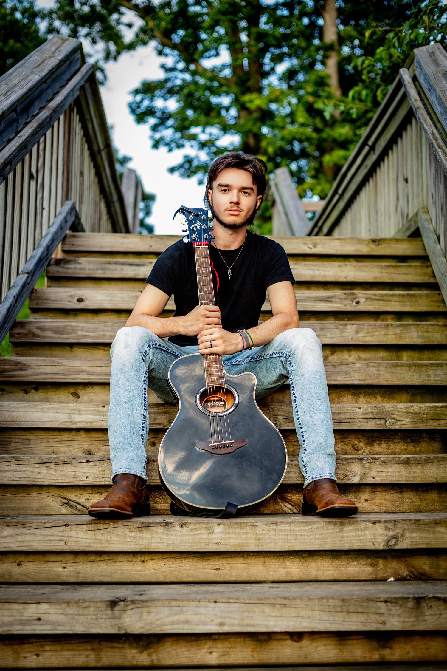 Musician portrait session with acoustic guitar on wooden amphitheater steps.
